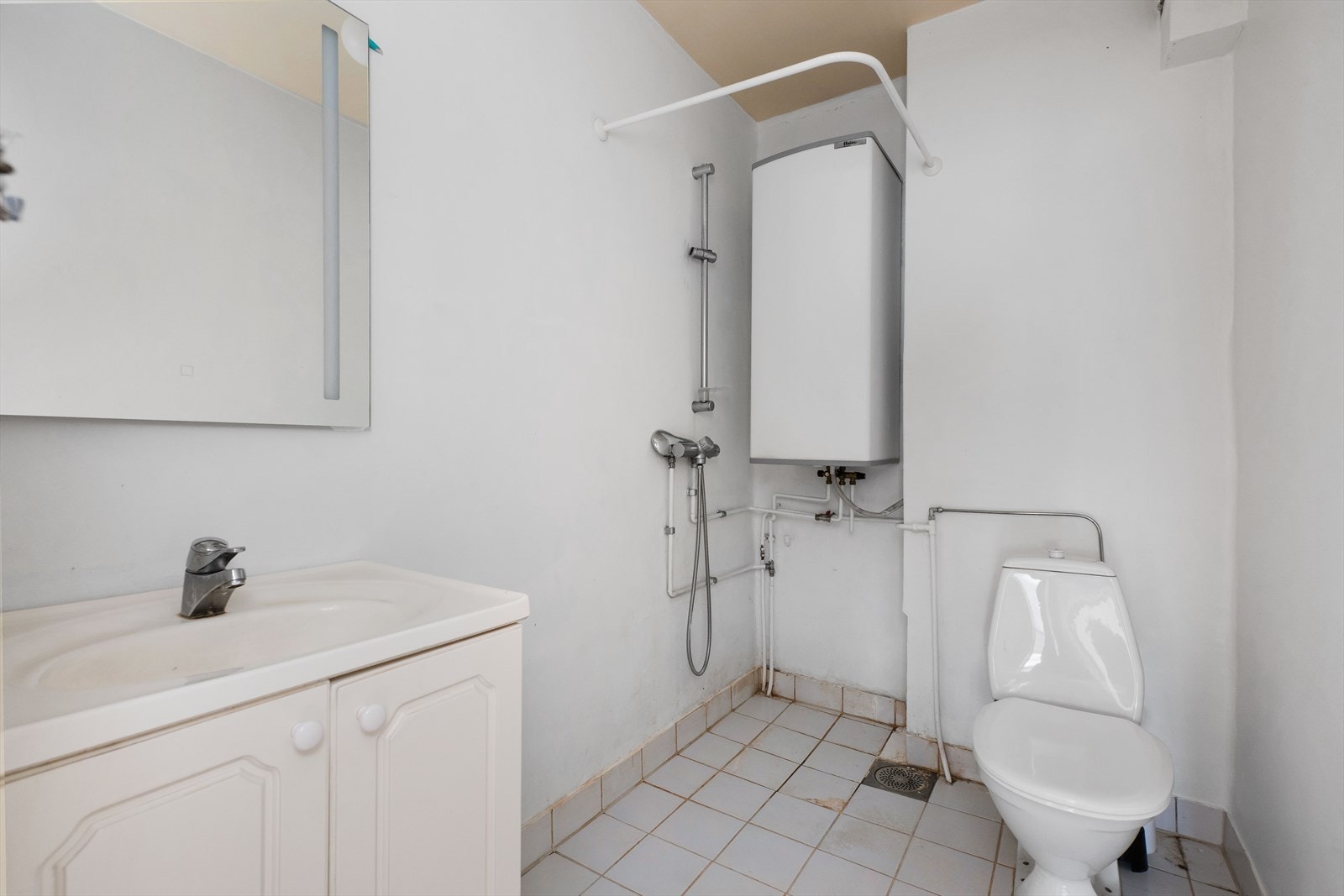 Eldre baderom med fliser på gulvet og baderomsstrie på veggene. Galleribilde