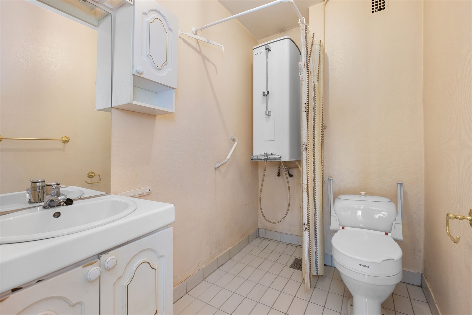 Eldre baderom med fliser på gulvet og baderomsinnredning i hvit utførelse. Galleribilde