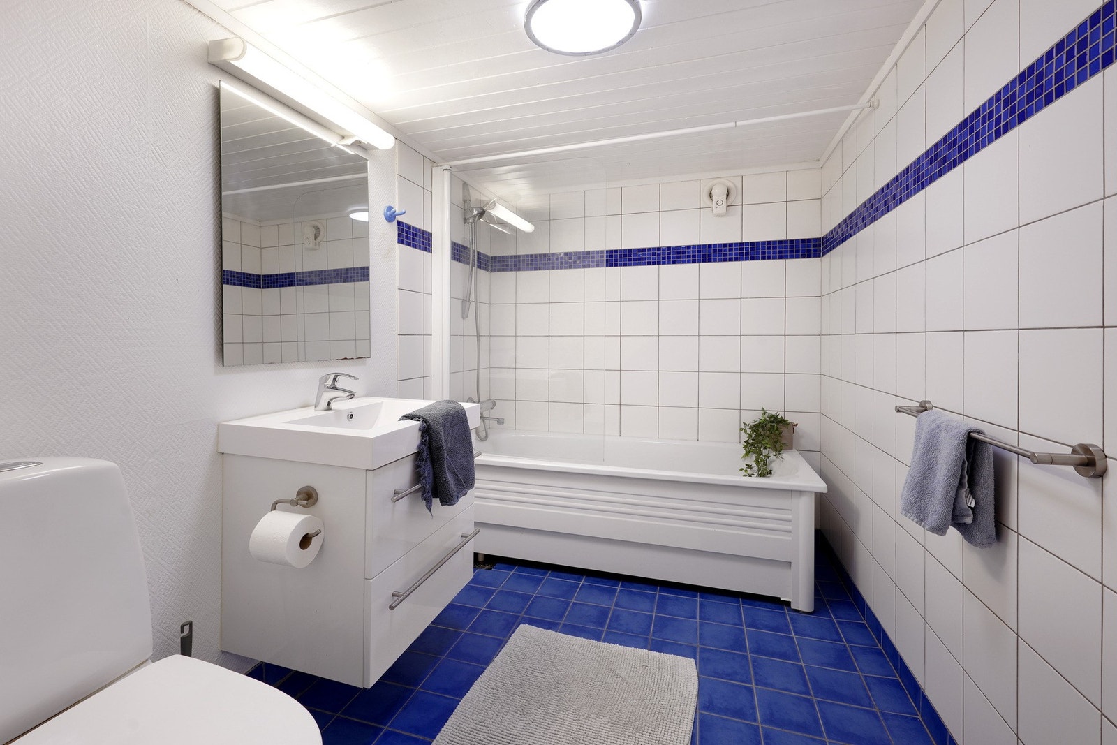 Bad i kjeller med fliser på gulv og badekar/dusjnisje. Galleribilde