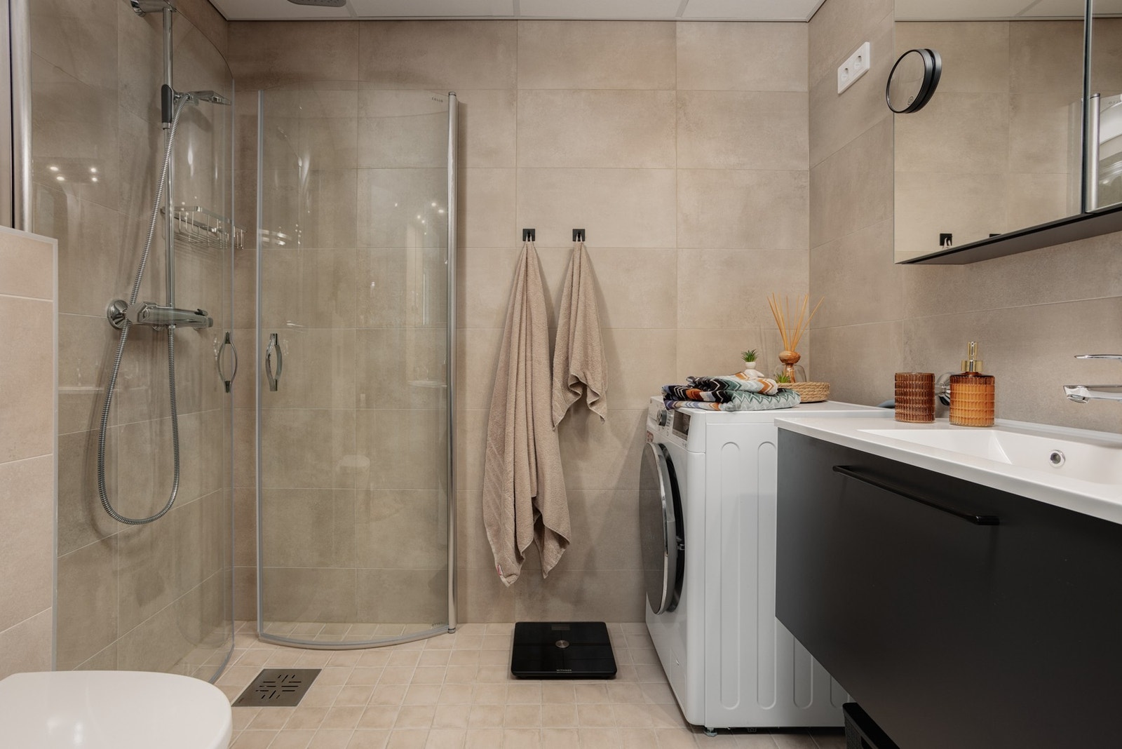 Flislagt bad med varmekabler i gulvet. Utstyrt med vegghengt toalett, servant, dusjhjørne og opplegg for vaskemaskin. Galleribilde