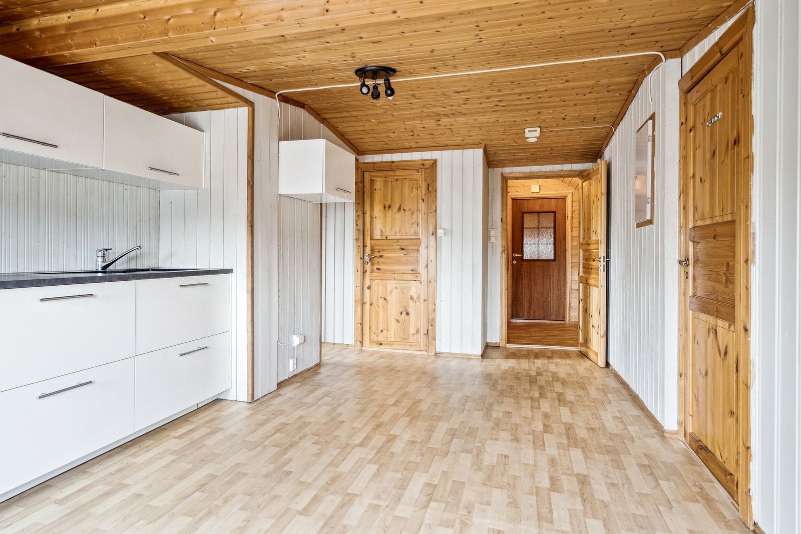 Gulv belagt med belegg samt vegger og himling av trepanel. Galleribilde