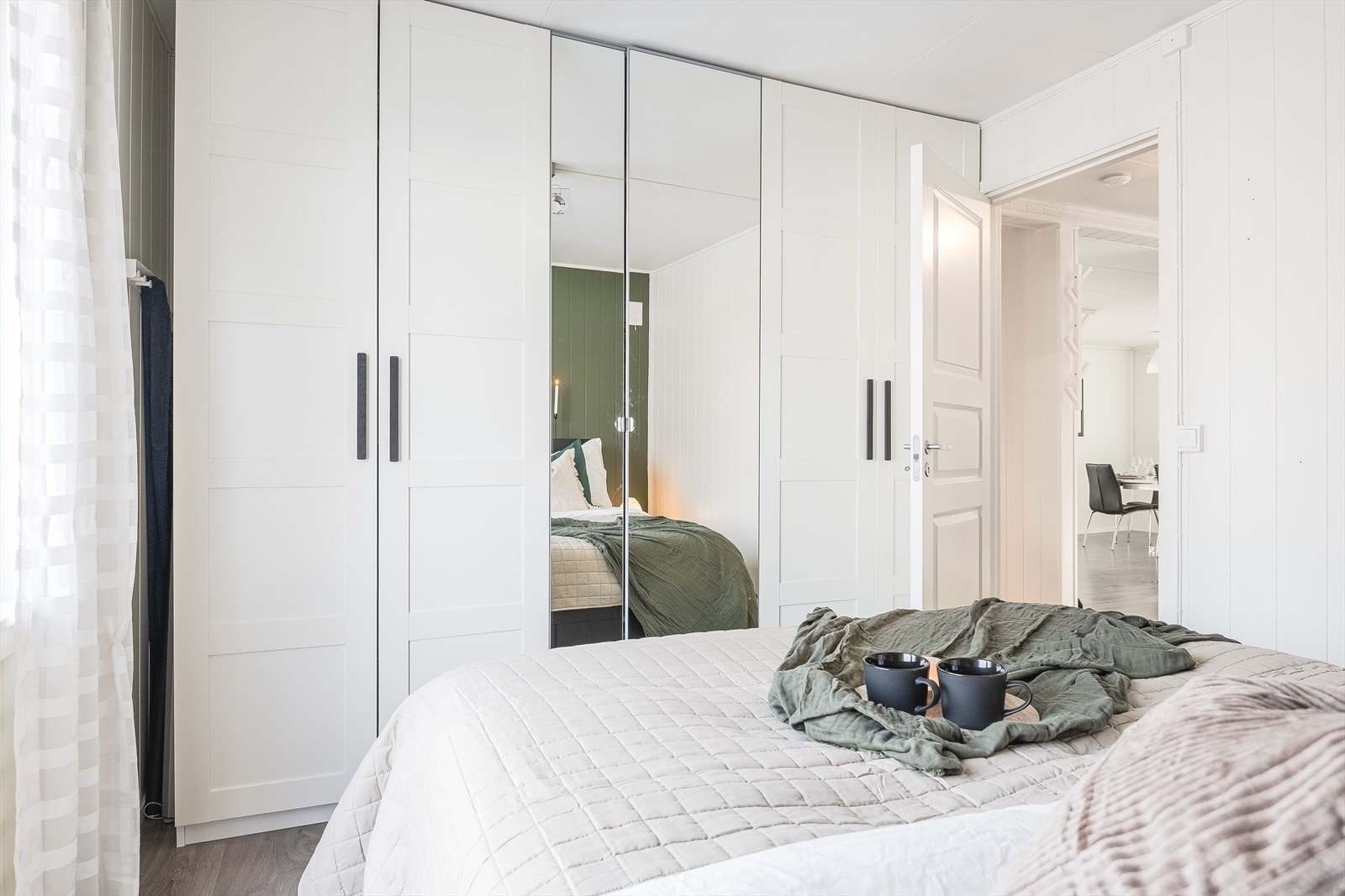 Lyst og romslig soverom med pen enstavs laminat på gulv og lyse panelplater på veggene. Garderobskap medfølger ikke. Galleribilde