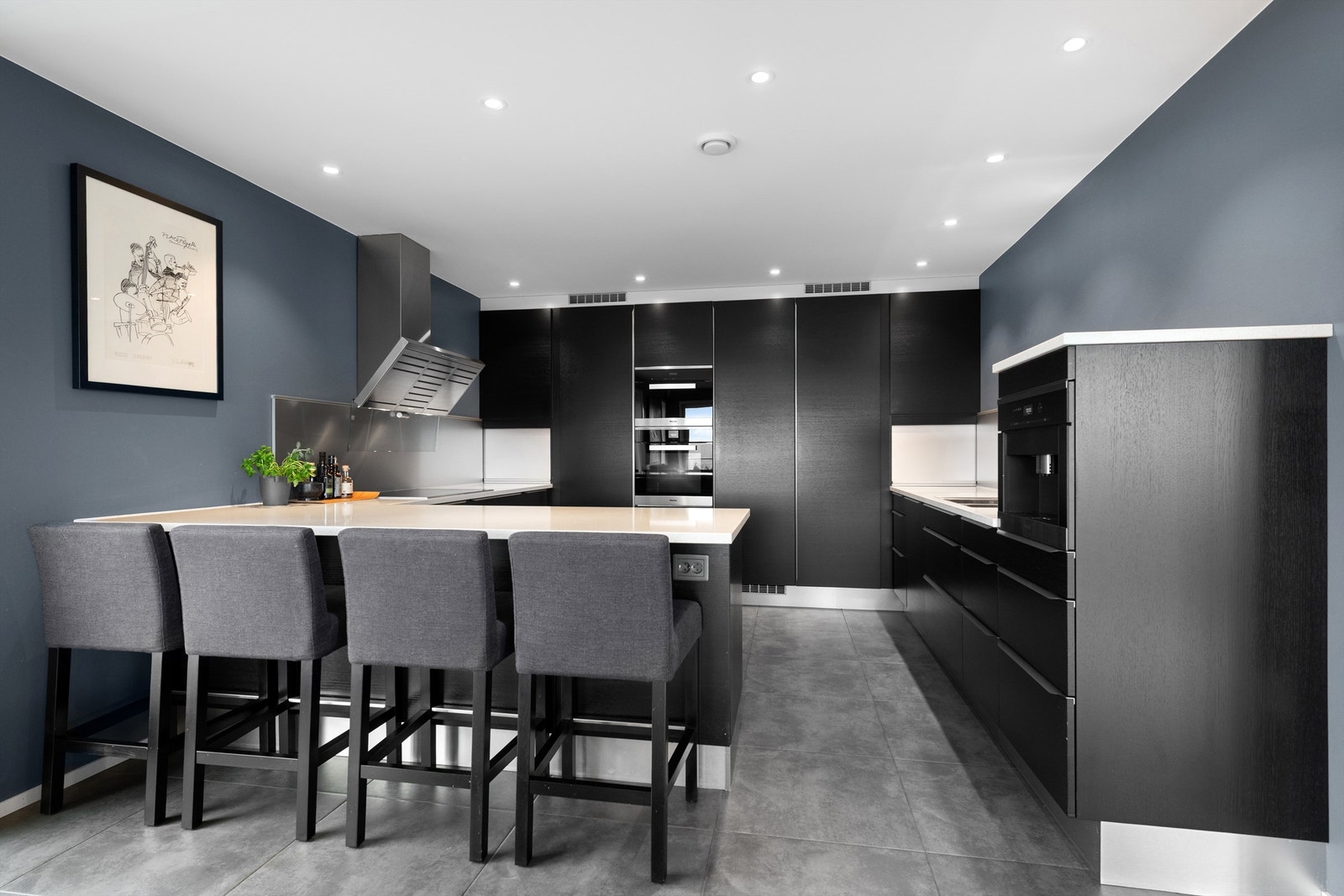 Kjøkkeninnredningen er fra HTH og har sorte glatte fronter og benkeplate av lys stein med nedfelt oppvaskkum med ett-greps kjøkkenarmatur Galleribilde