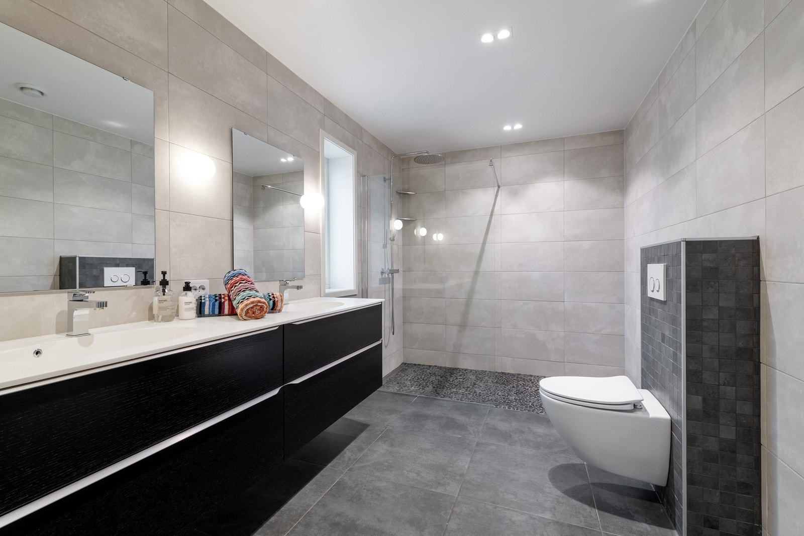 Stort bad med dobbel servant i 1. etasje. Dusjnisje med glassvegg og vegghengt dusjarmatur med hånddusj og regndusj. Vegghengt toalett Galleribilde