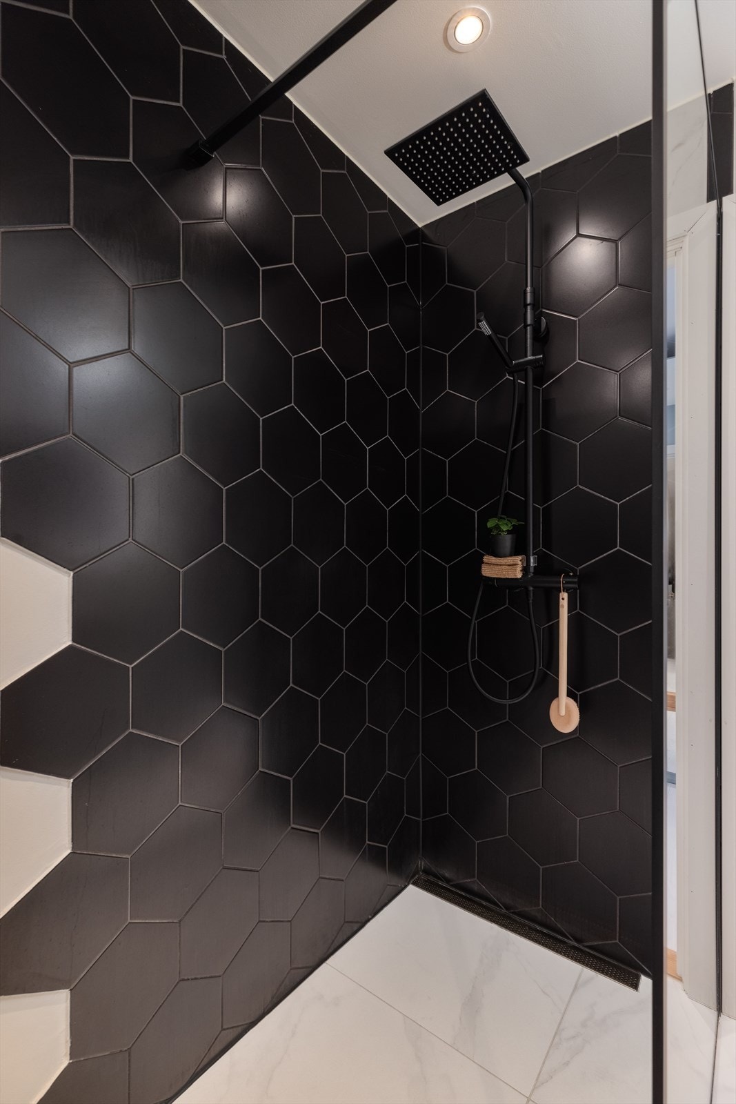 Badet er flislagt med lyse delikate marmorfliser (calacatta fra MUSE) på gulv og vegger, mens dusjsonen og deler av veggen har mørke fliser i et kult mønster som skaper en fin kontrast. Galleribilde