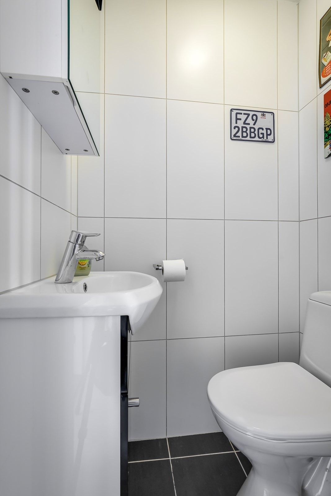 Separat, flislagt toalettrom med frittstående toalett, servant med underskap og speilskap. Galleribilde