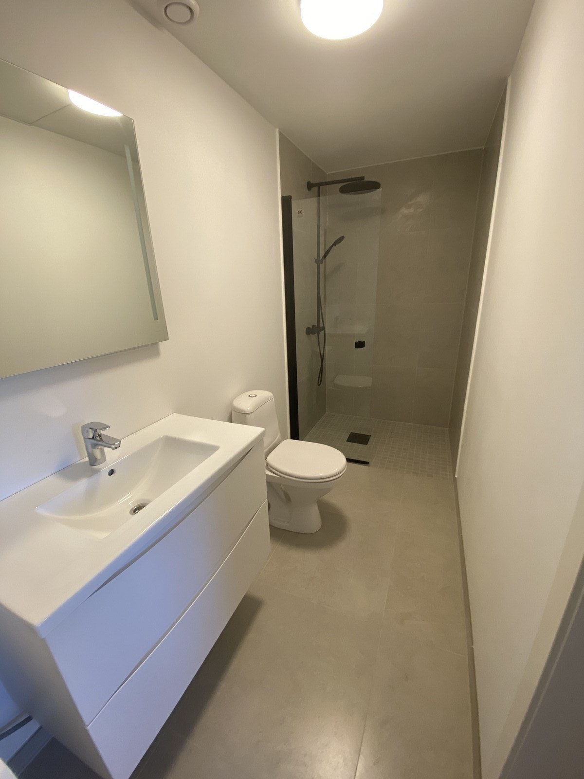Badet er innredet med toalett, servant på innredning og dusjnisje Galleribilde