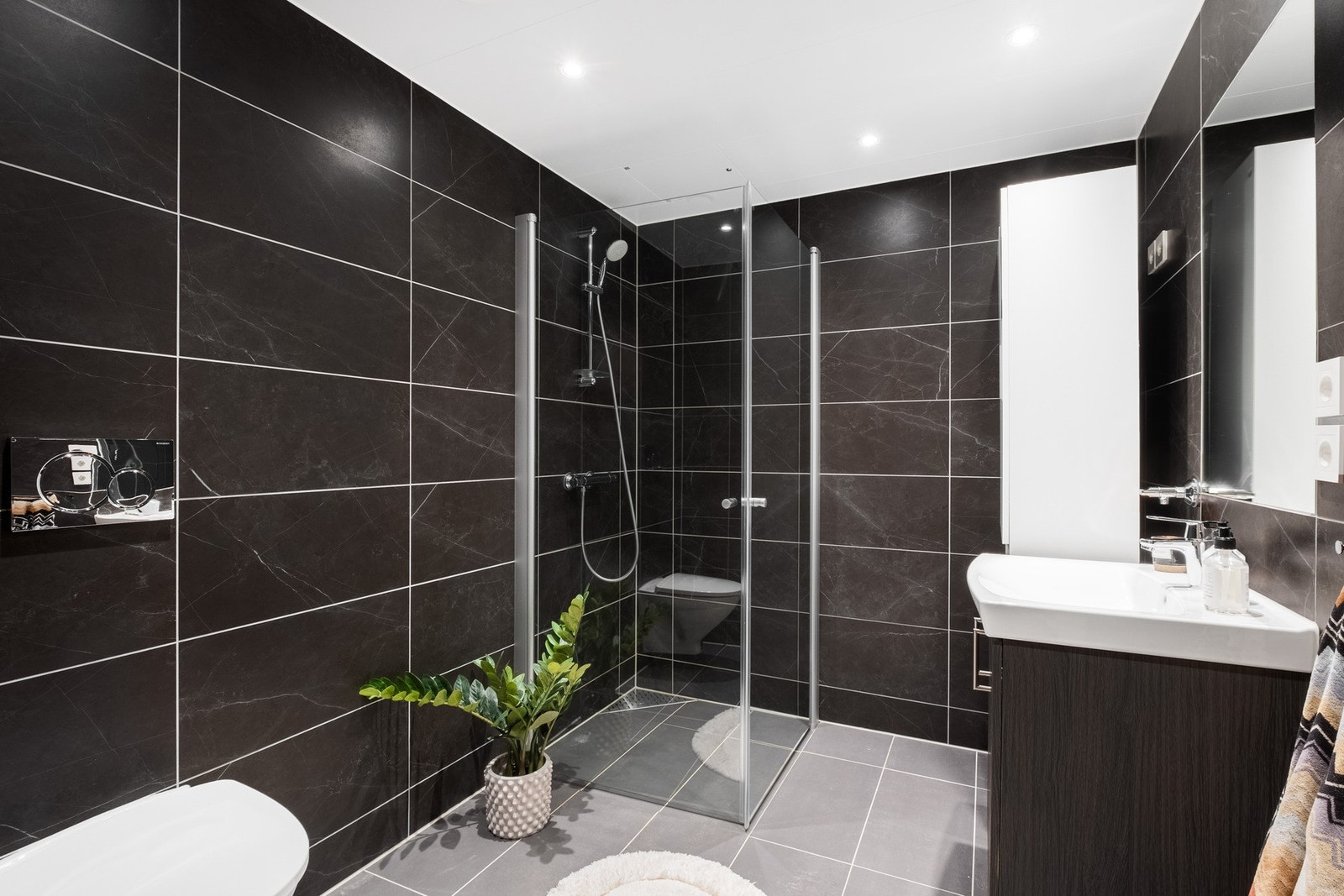 Det flislagte badet holder et moderne og avslappende preg med mørke veggfliser. Galleribilde