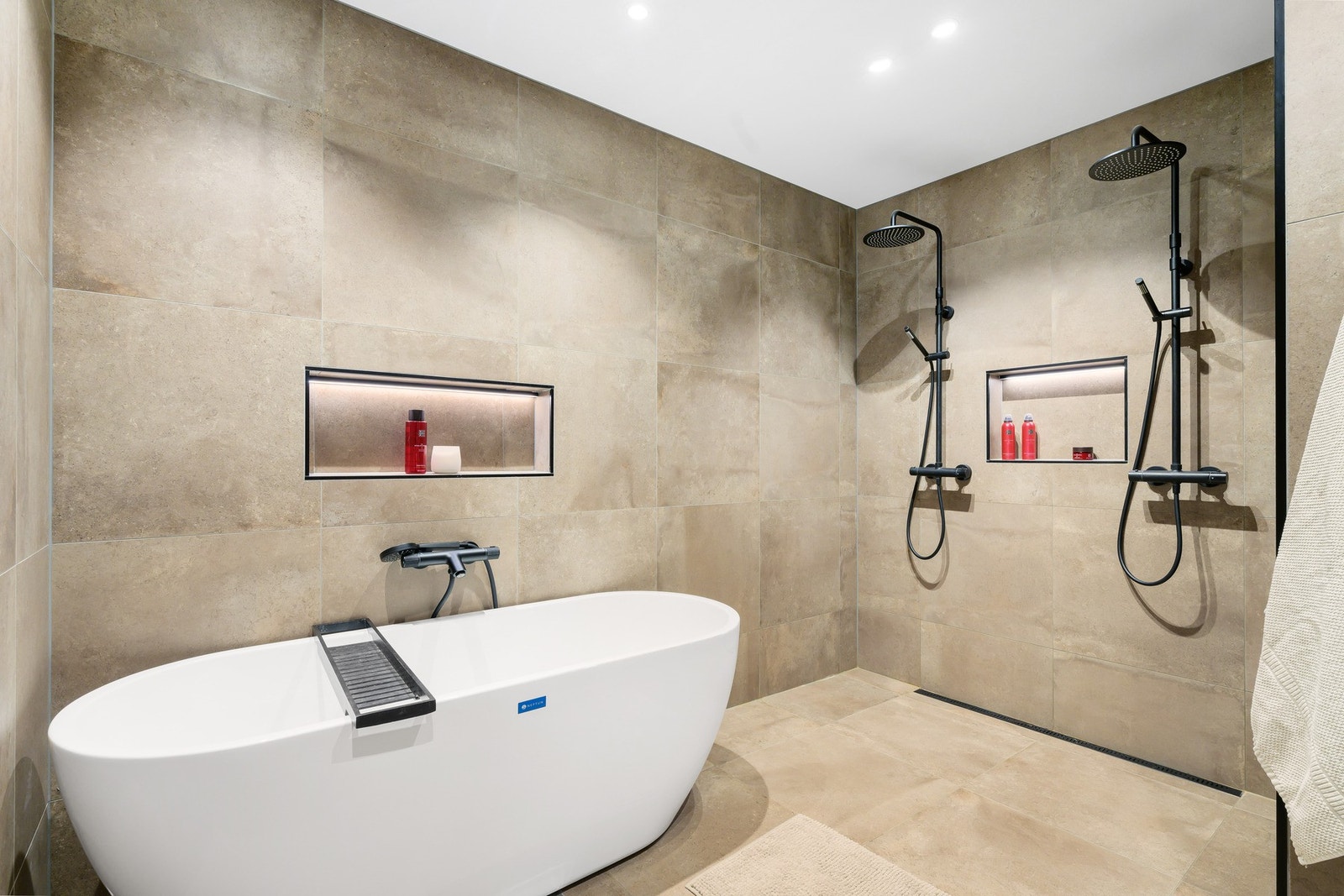 Baderomsinnredningen består av badekar, dusj, to servanter, plassbygde møbler og veggmontert wc. Galleribilde