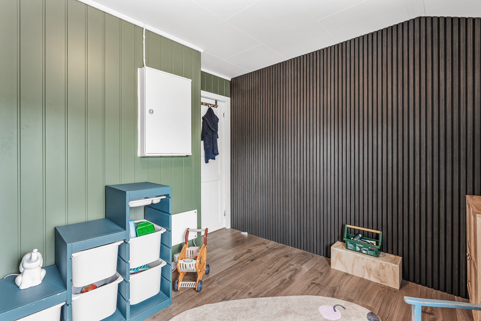 Veggflatene er kledd med malt panel og spiler, mens det på gulv er laminat Galleribilde