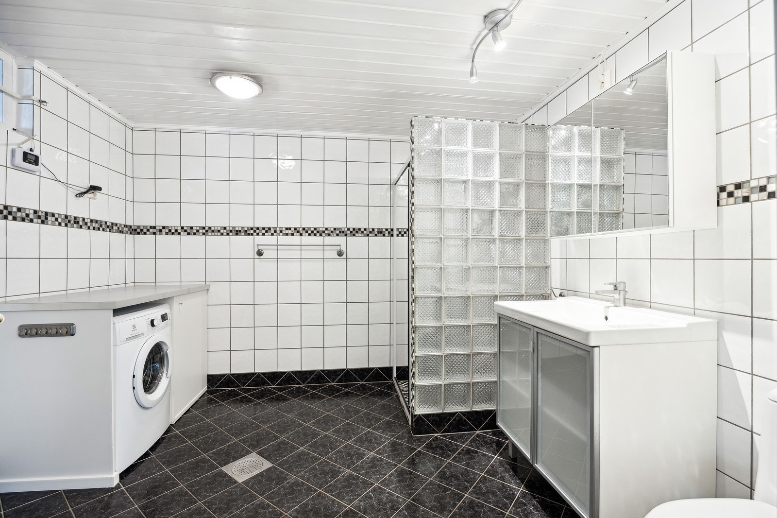 Romslig bad med vaskemaskin, toalett, servant og dusj. Galleribilde