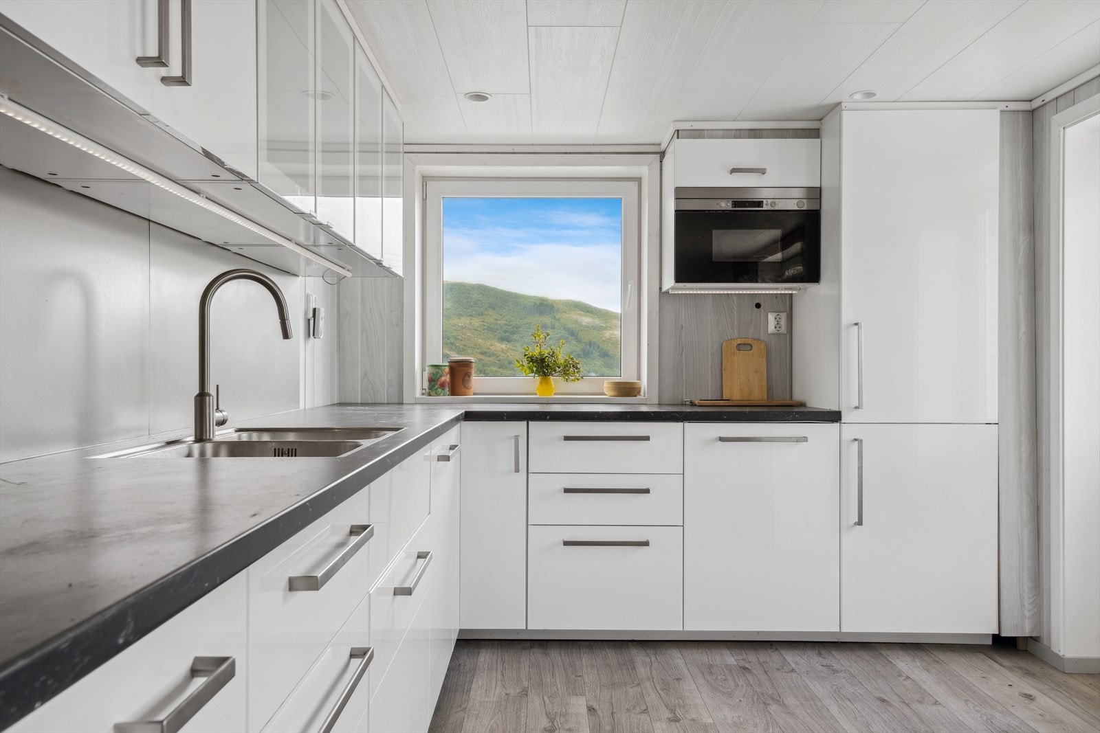 Kjøkkenet fremstår relativt strøkent med integrerte hvitevarer og møblering fra IKEA. Galleribilde