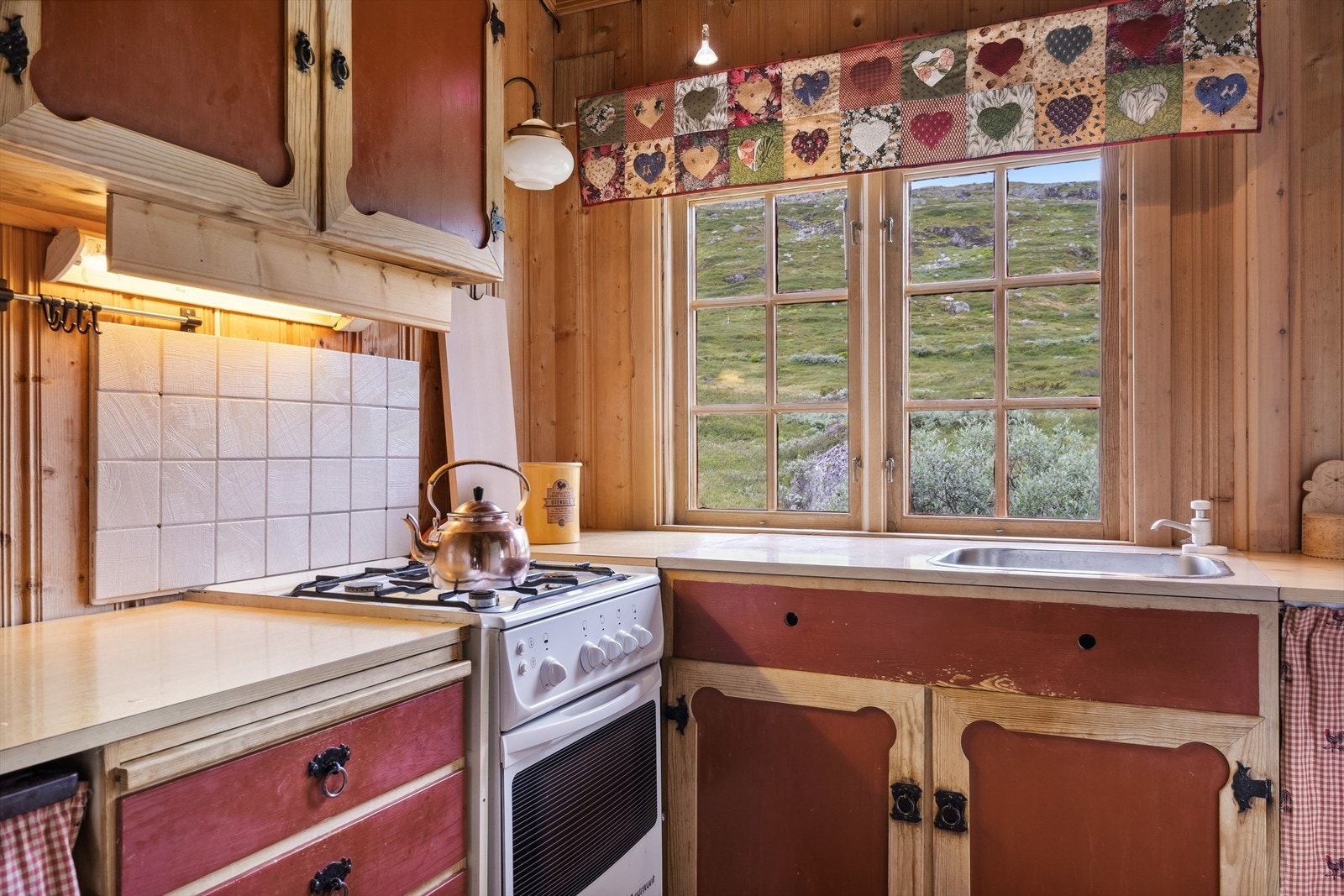 Kjøkkenet har innredning av heltre med malte glatte fronter, gasskomfyr og elektrisk/gassdrevet kjøleskap. Galleribilde