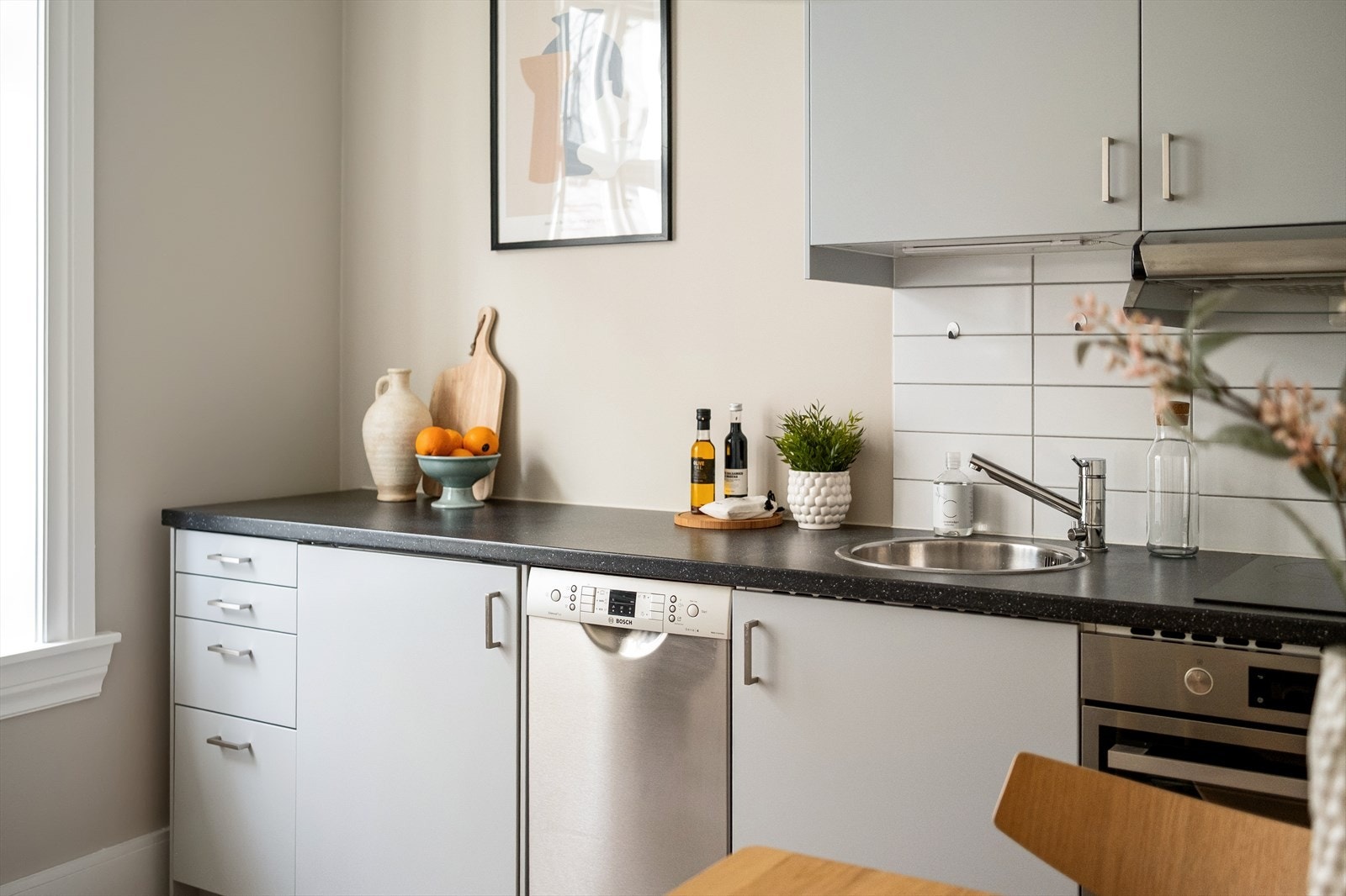 Tidsriktig glatt innredning fra IKEA, soft close, takoppforing, led lys under overskap, fliser over deler av benk, laminat benkeplate med nedfelt stålkum og keramisk topp, integrert kombi micro/komfyr, oppvaskmaskin (smal type), kjøleskap. Galleribilde