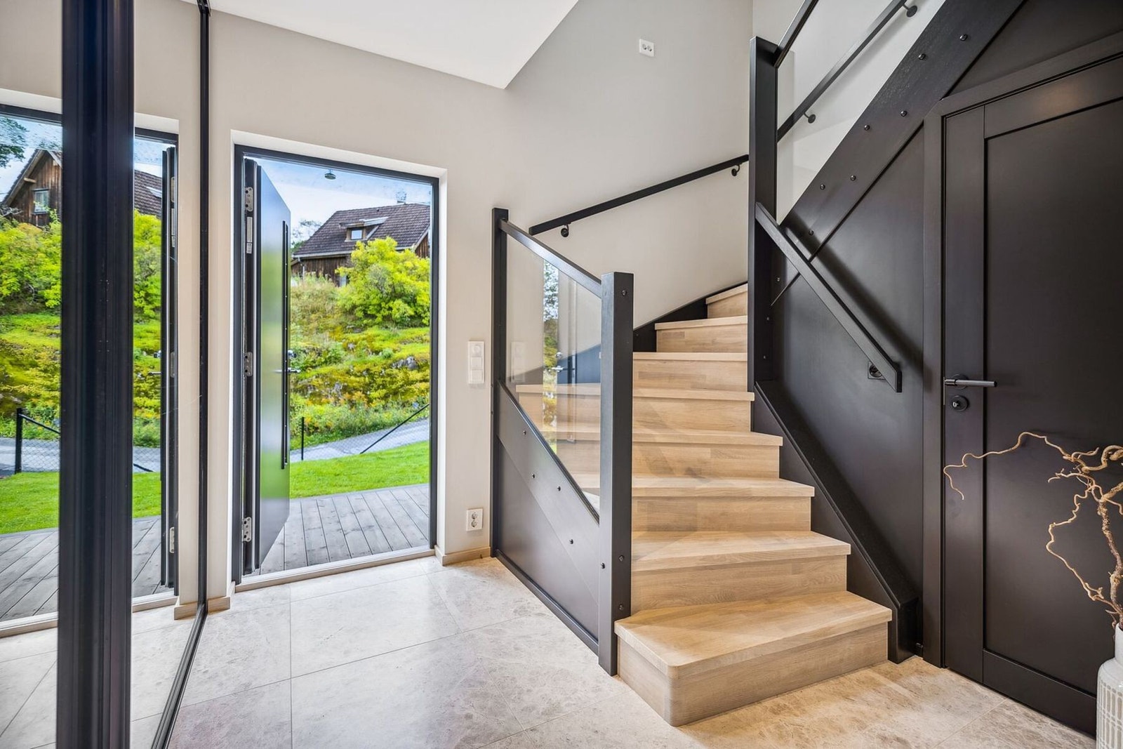 Entreen er flislagt med varme i gulv og tilbyr rikelig med oppbevaring i både skyvedørsgarderobe med speilfronter og eget trapperom til oppbevaring.. Galleribilde