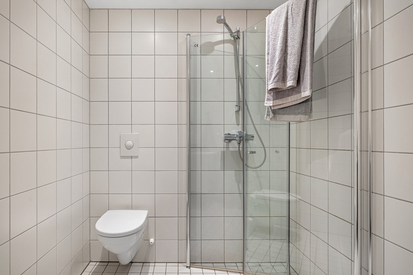 Romslig dusjnisje bak innfellbare dusjdører i glass. Galleribilde