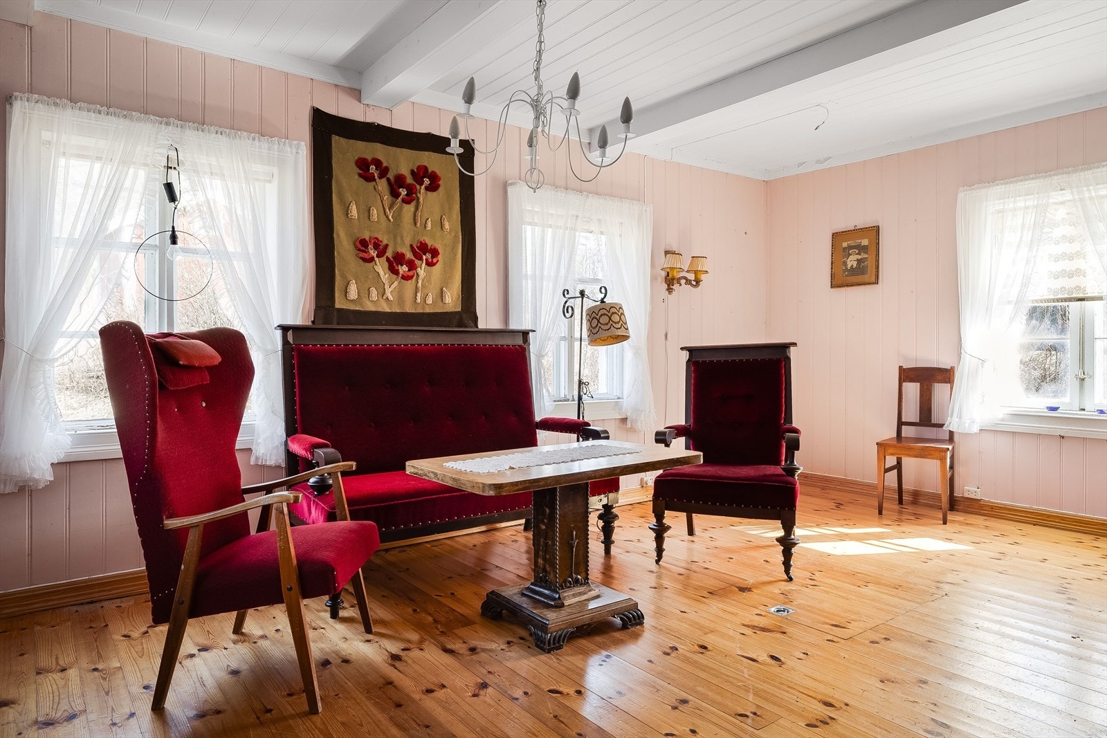 Lys og sjarmerende stue med lakkerte tregulv og panel på veggene malt i en dus rosafarge. Galleribilde