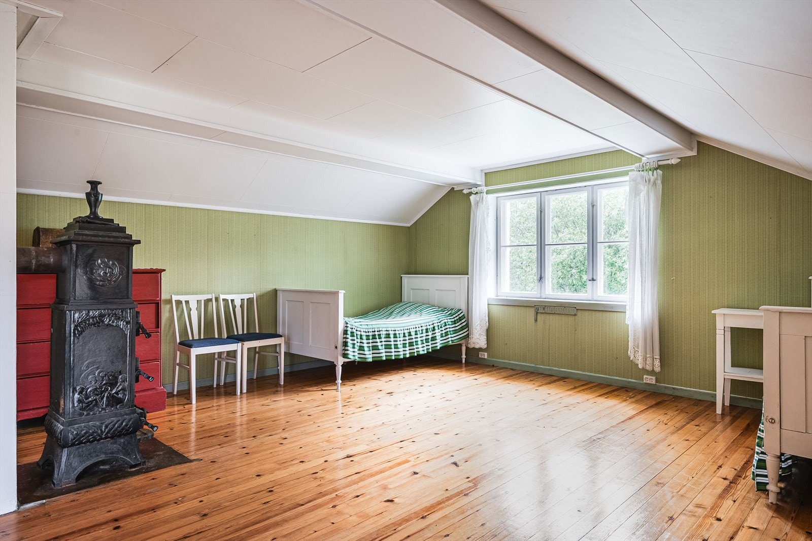 Soverommet har lakkerte tregulv, malt panel på veggene og en sjarmerende eldre vedovn. Galleribilde