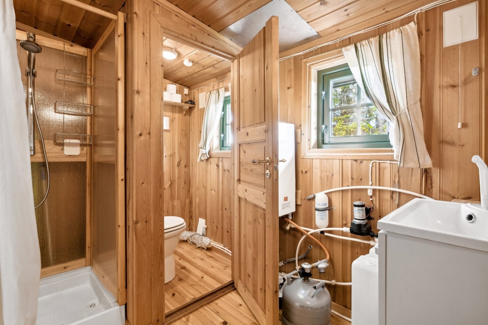 Badet er opprinnelig bod, les punkt "ferdigattest" i salgsoppgaven. Det er dusjkabinett og servant her, samt inngang til toalettrom med snurredass. Det er vannpumpe som henter vann fra tank på gulv og gassvannvarmer for varmtvann. Galleribilde