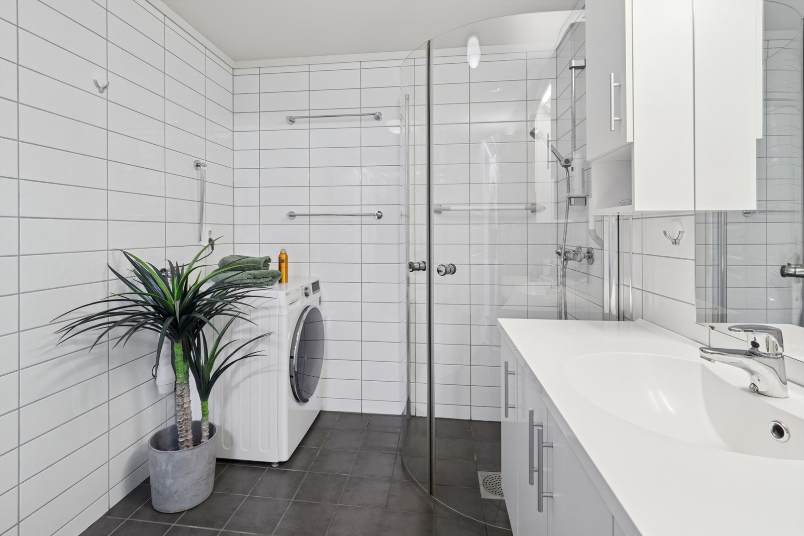 Stilrent baderom innredet med romslig servantinnredning, speil med lys, toalett og dusjhjørne. Galleribilde