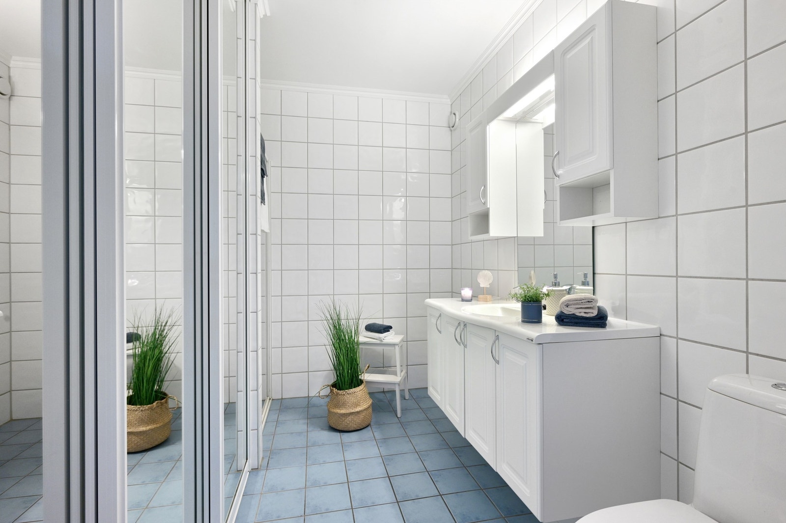 Flislagt baderom med toalett, servant i baderomsinnredningen, dusj og opplegg til vaskemaskin Galleribilde