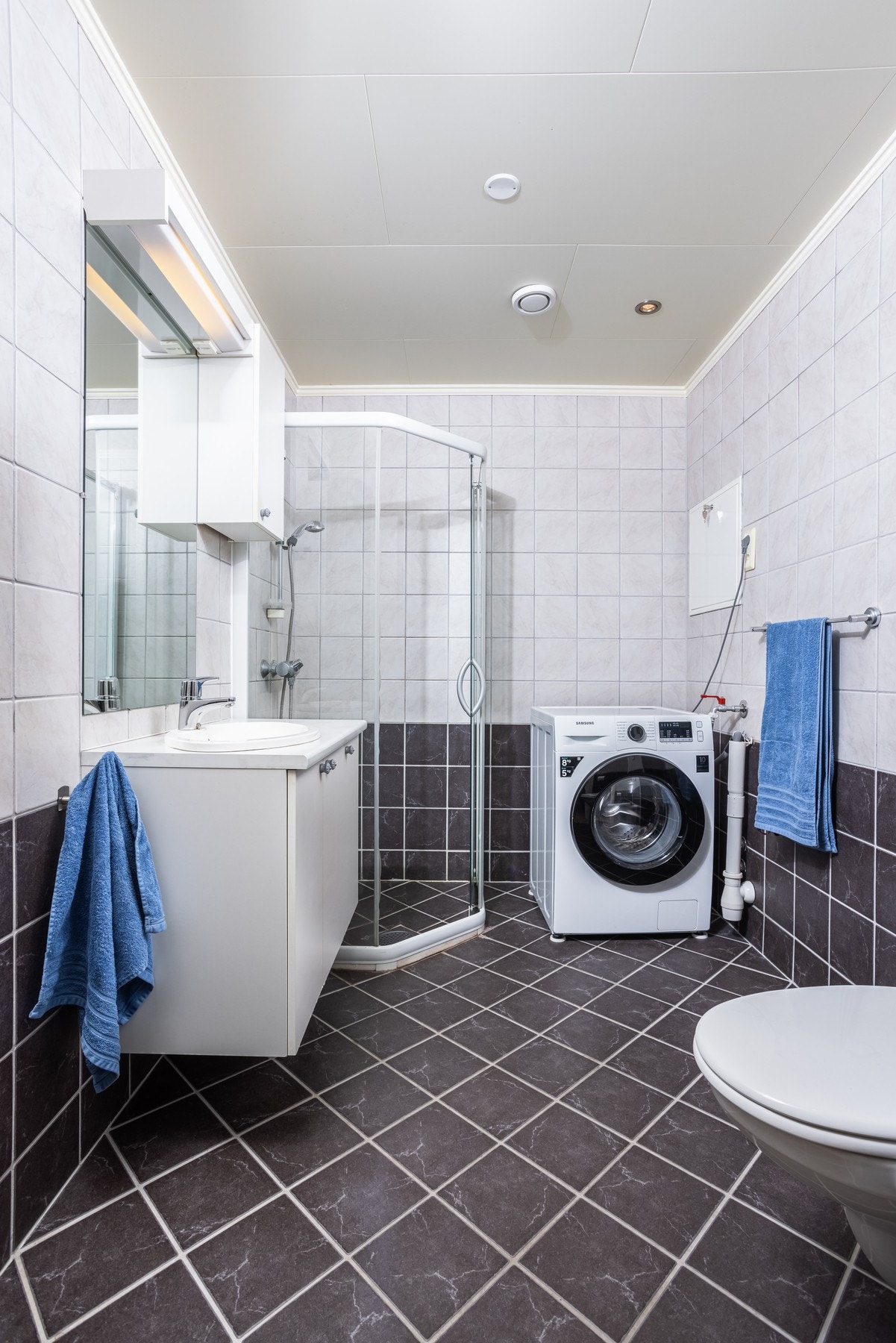 Badet er flislagt på gulv og vegg. Opplegg for vaskemaskin og dusjhjørne. Galleribilde