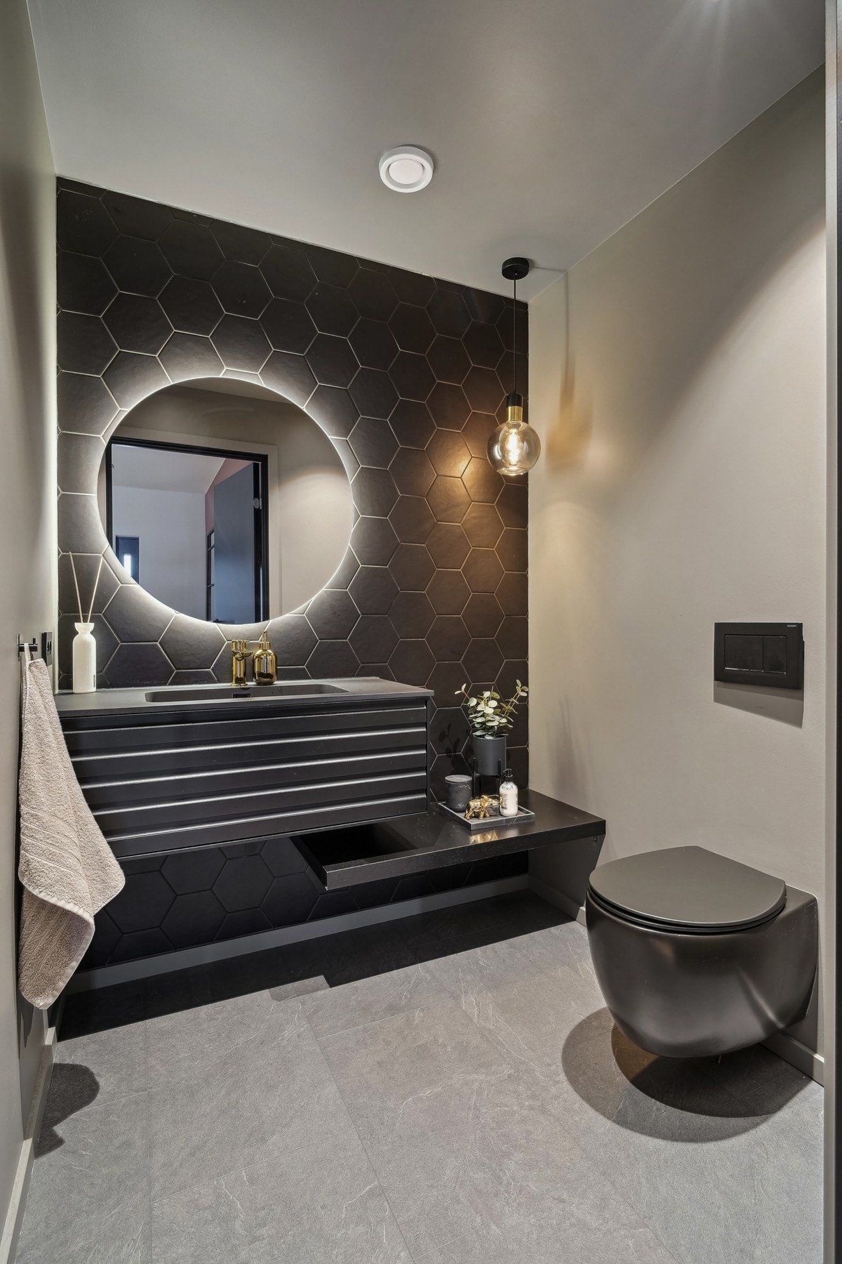 Gjestetoalettet er lekkert innredet og holdt i dempede farger med lun belysning og sorte heksagonfliser. Galleribilde