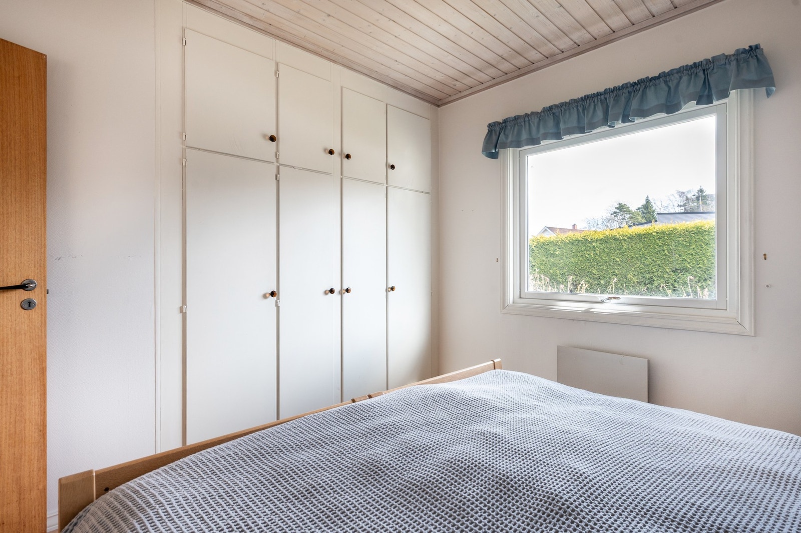 Det er plassbygde garderobeskaper i veggen til naborommet. Galleribilde