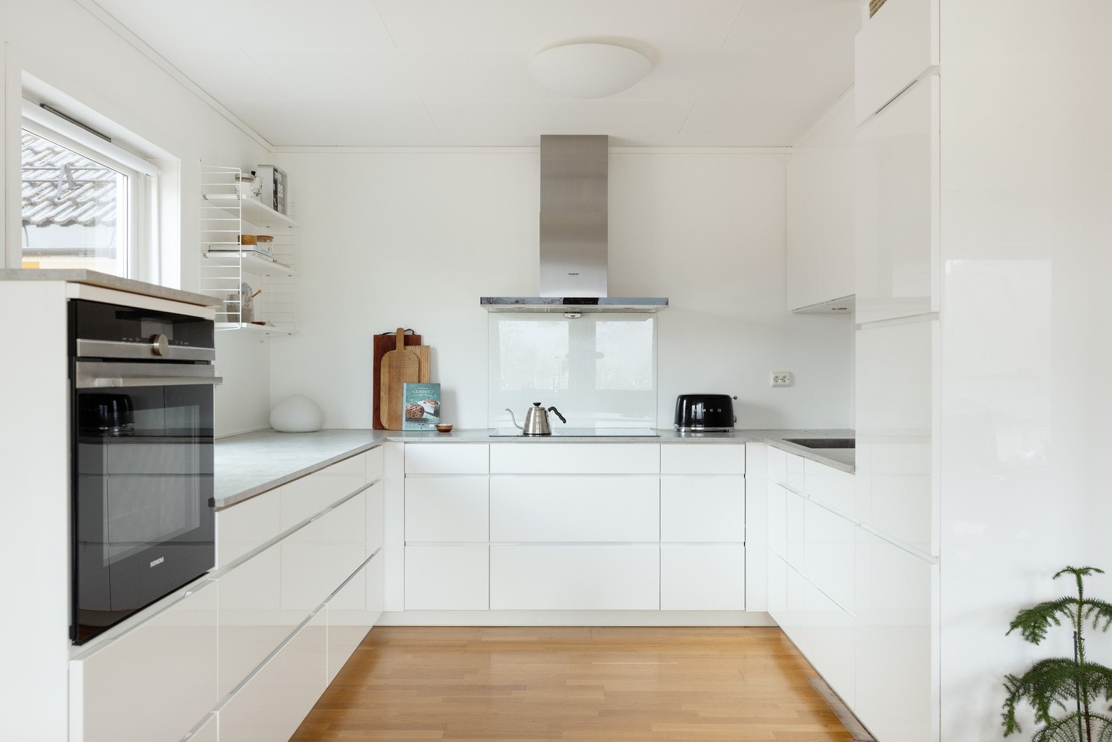 Innredningen har hvite, slette fronter, benkeplate i kompaktlaminat med glassplate på vegg bak platetopp, ventilator og integrerte hvitevarer. Galleribilde