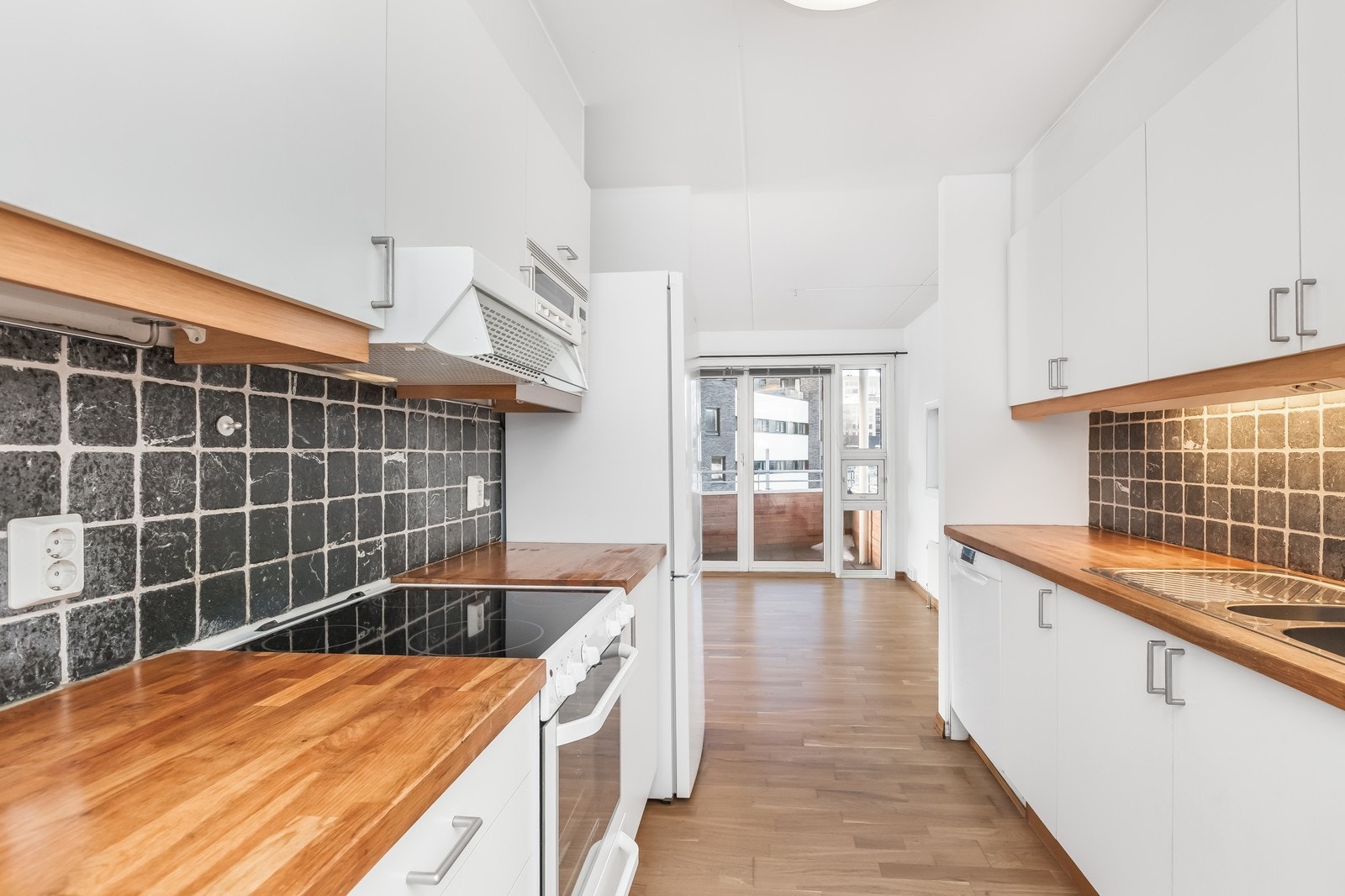 Kjøkken med heltre benkeplate og hvitevarer. Galleribilde