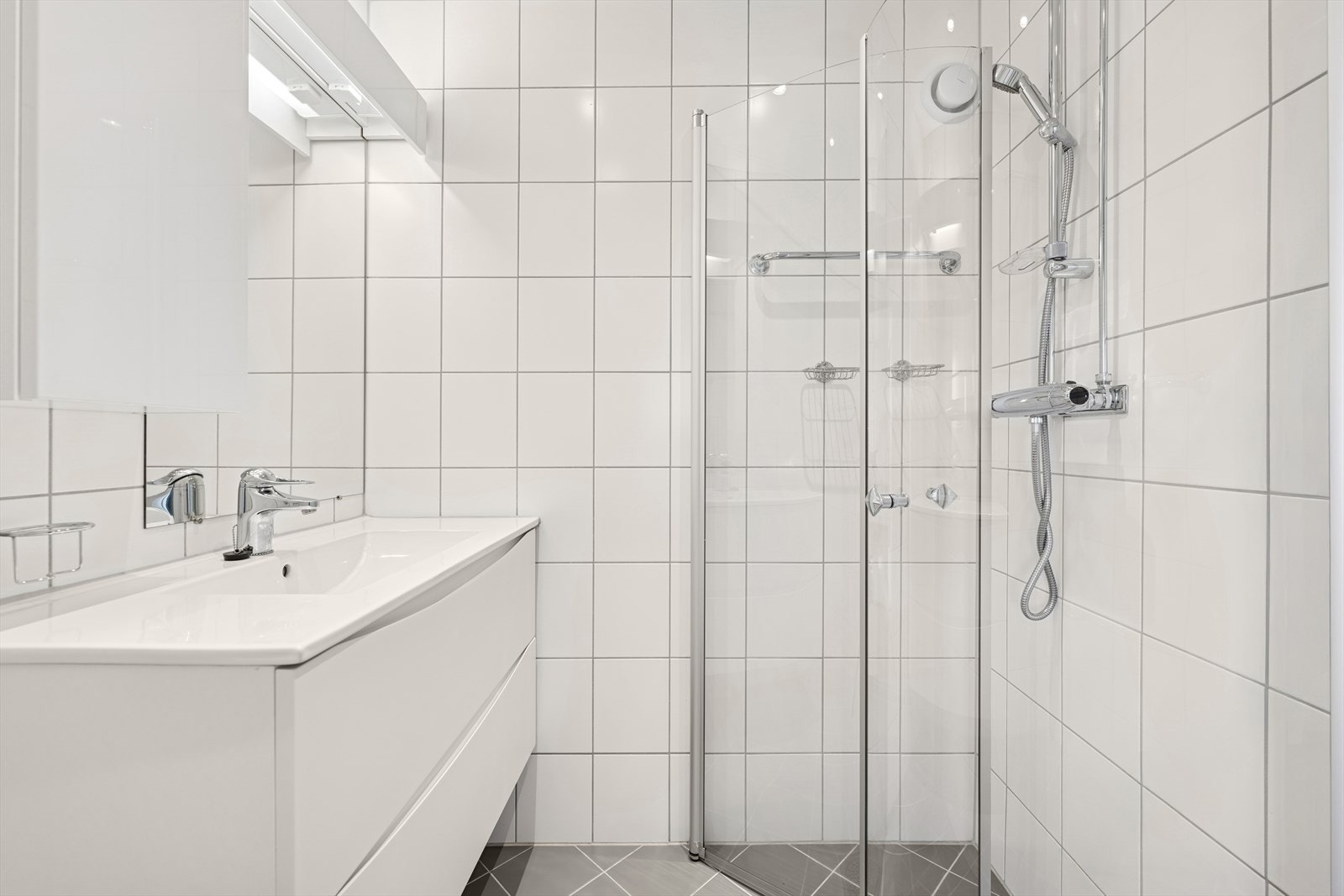 Badet ble renovert i 2016 i regi av borettslaget. Her finner du en tidløs standard med hvite veggfliser og lys grå gulvfliser med varmekabler. Galleribilde