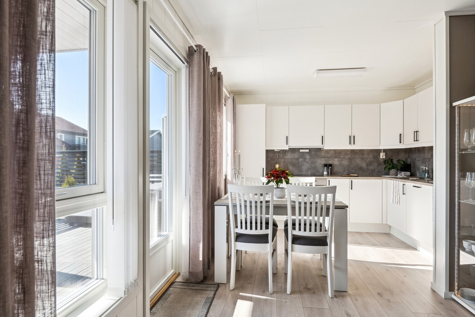 Fin åpen løsning til kjøkkenet. Store vinduer og dør ut til balkongen sørger for rikelig med dagslys. Galleribilde