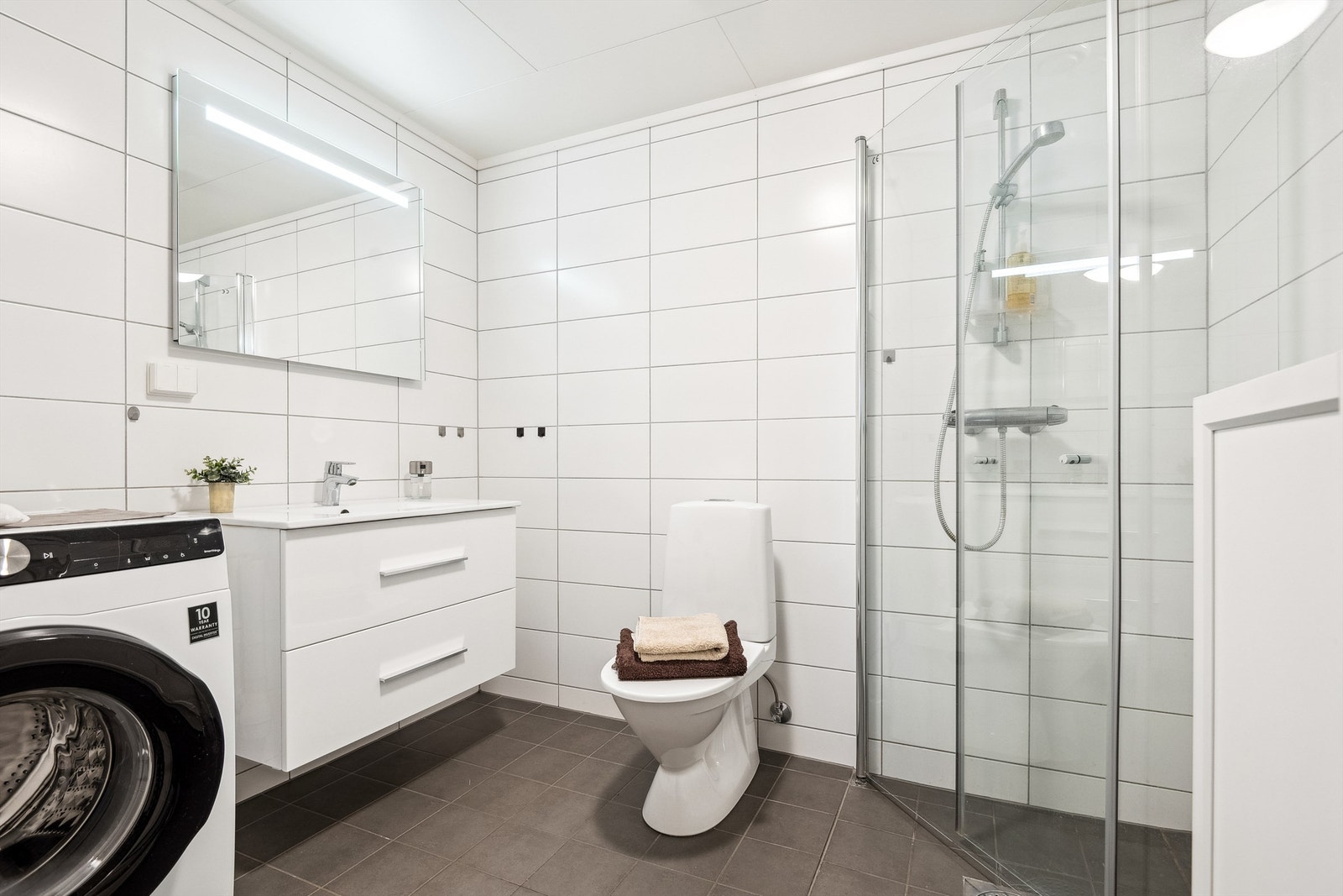 Badet fremstår moderne og funksjonelt med flislagte gulv og vegger, samt himlingsplater i taket. Det er vannbåren gulvvarme. Galleribilde