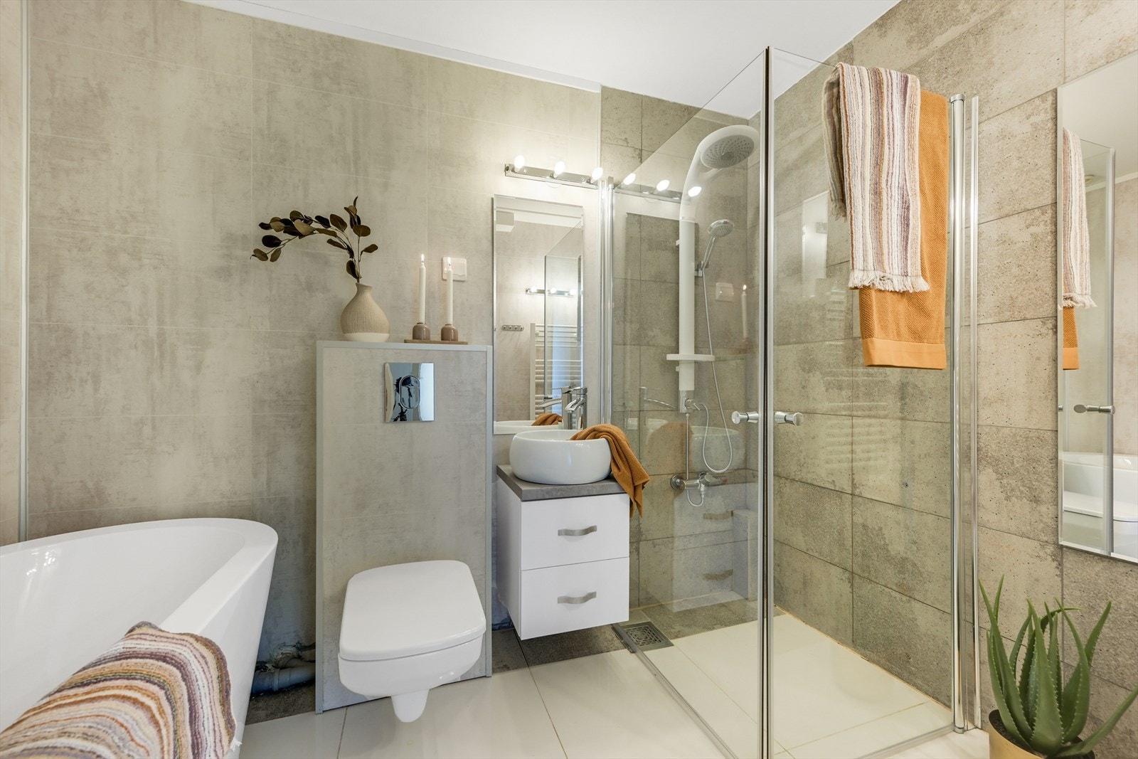 Pen bad/wc med badekar, dusjhjørne, vegghengt toalett og tøff servant. Galleribilde