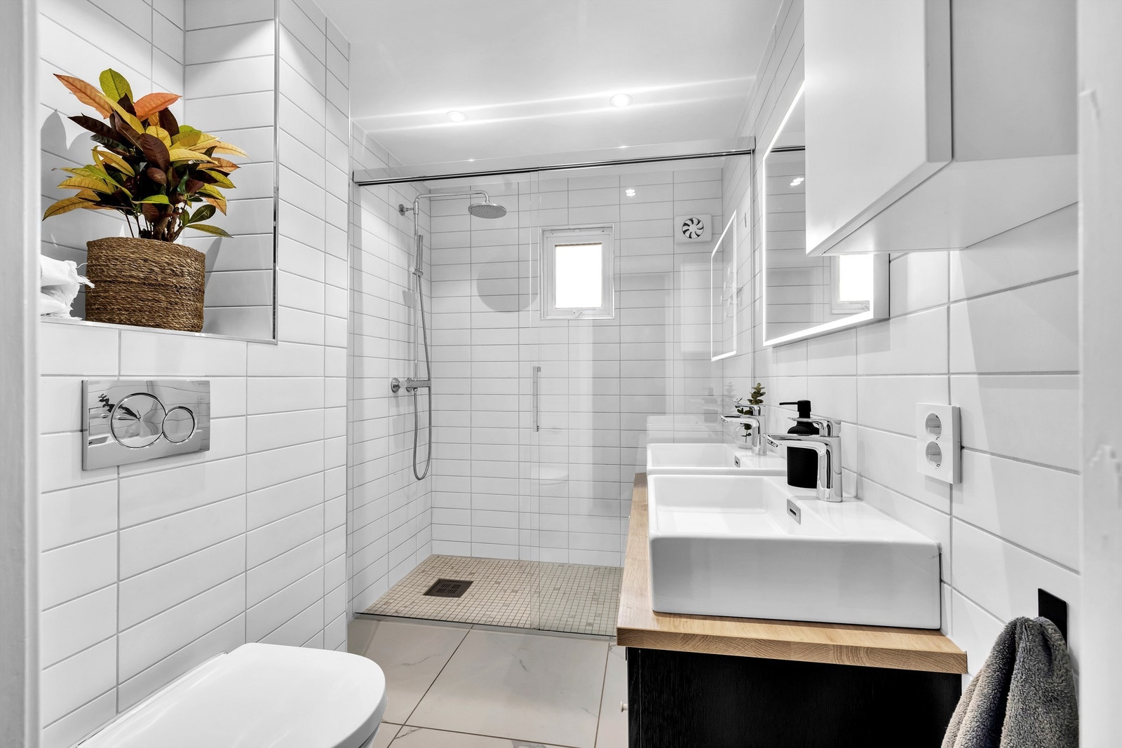 Dobbel servant, dusjnisje med glassdører og vegghengt toalett. Galleribilde