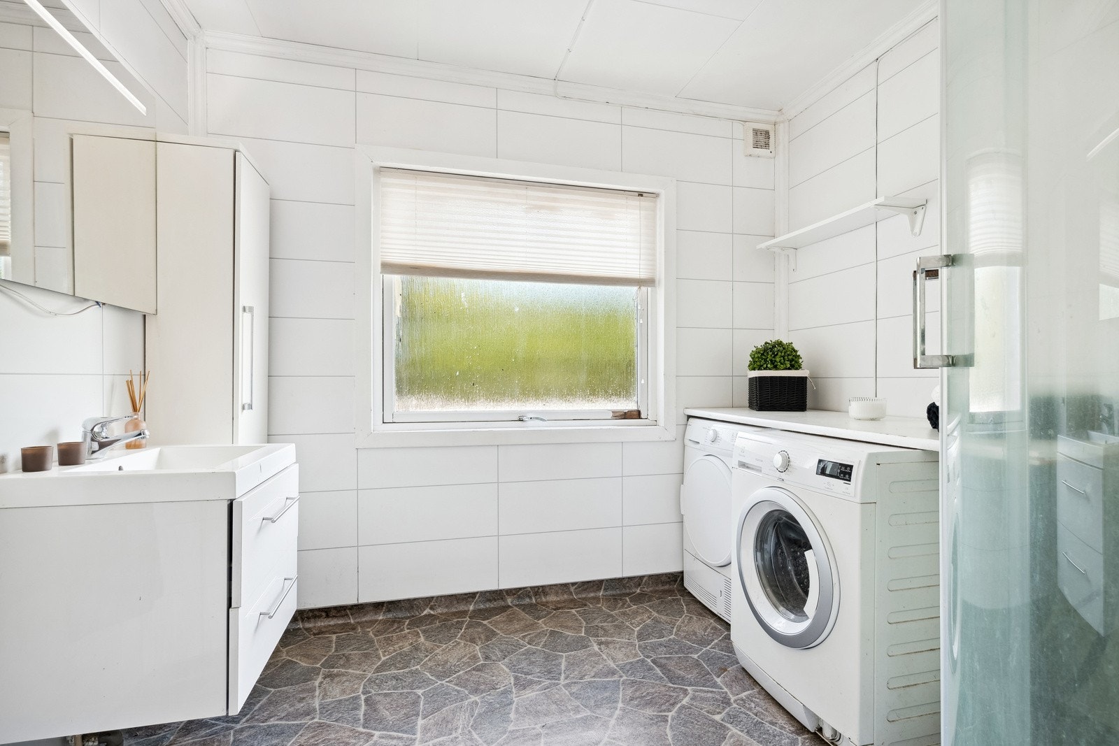 Badet i hovedetasjen er innredet med dusjkabinett, servant med underskap og opplegg for vaskemaskin. Galleribilde