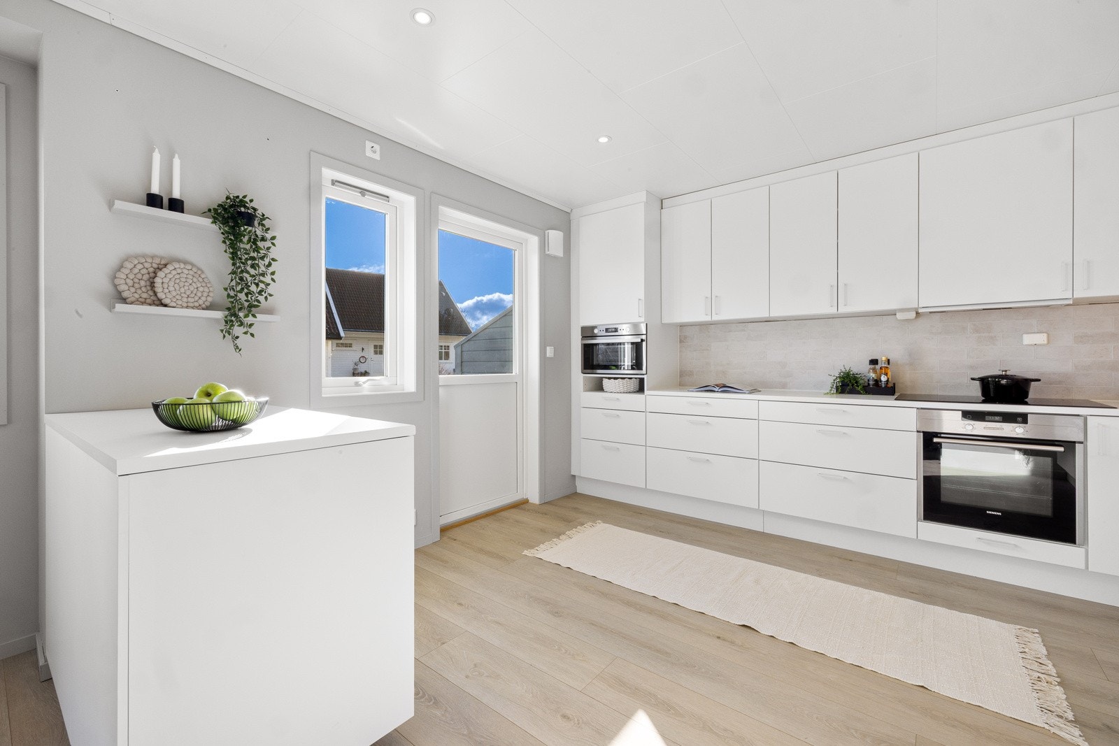 Kjøkkeninnredning med glatte hvite fronter og godt med skapplass i både under- og overskap. Galleribilde