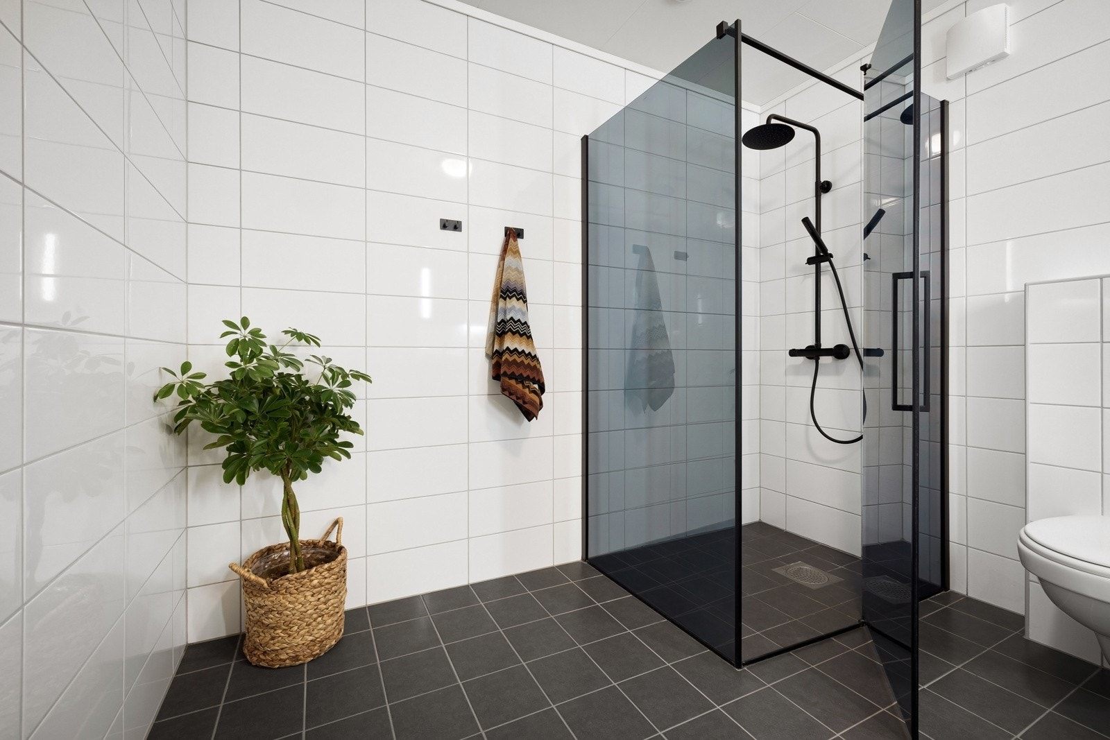 Rommet er innredet med innredning med to nedfelte servanter, veggmontert toalett og dusjvegger/hjørne. Galleribilde