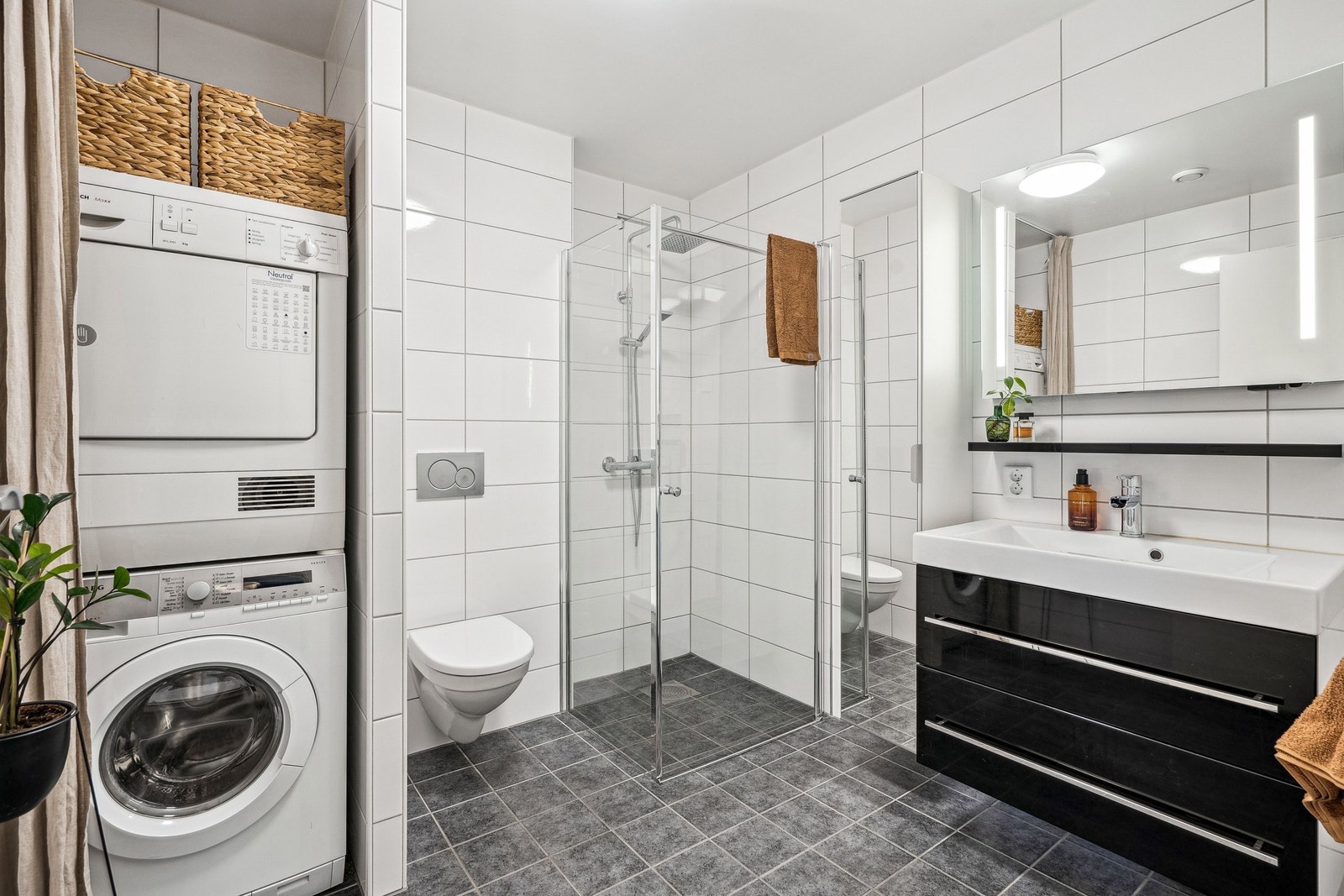 Gulvfliser i gråtone. Hvite fliser på vegger. Vegghengt wc. Vannbåren varme i gulv. Opplegg for vaskemaskin og tørketrommel Galleribilde