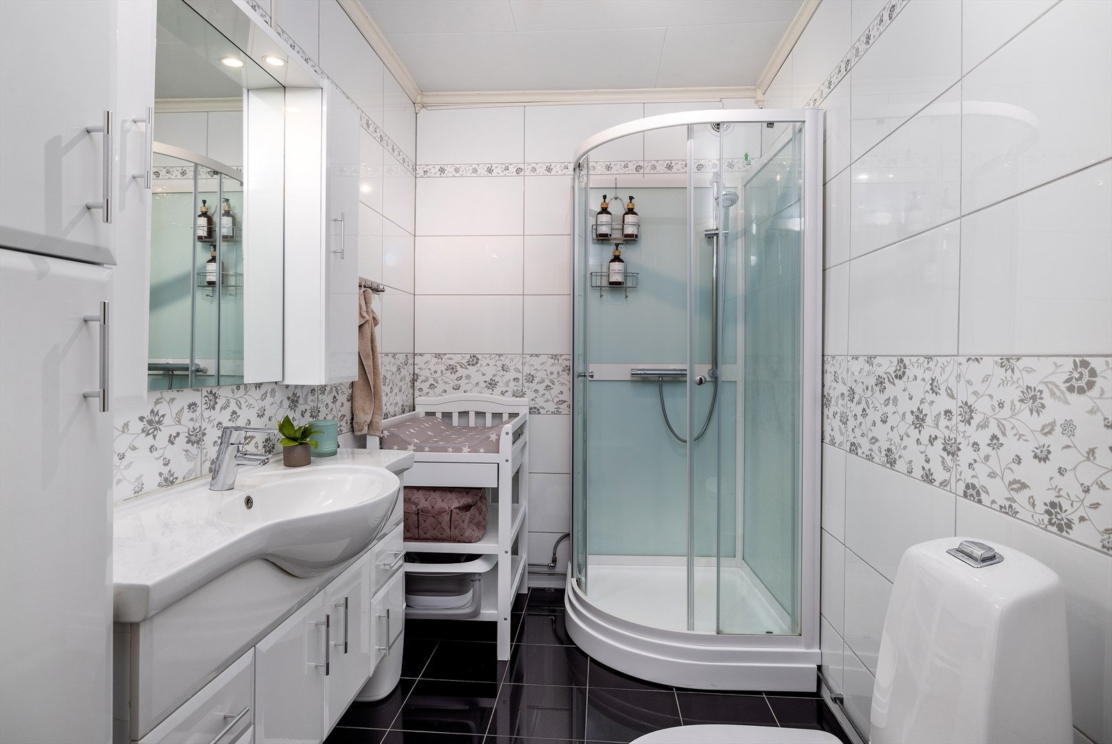 Badet ligger i 1. etasje og er pent innredet med servant på baderomsinnredning, toalett og dusjkabinett. Galleribilde