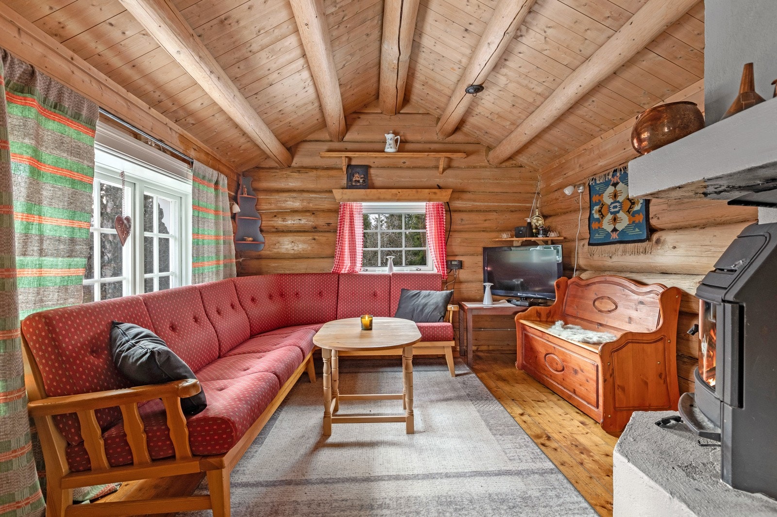 Hyggelig stue i hytta. Bestående av eldre tømmerkasse med tømmeråser og bordkledning. Galleribilde