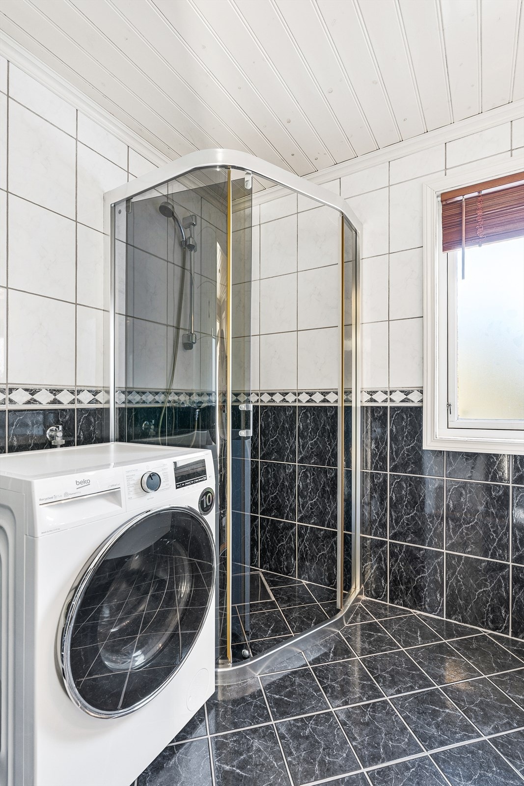Badet er utstyrt med servant med underskap, toalett, dusjhjørne og opplegg for vaskemaskin Galleribilde