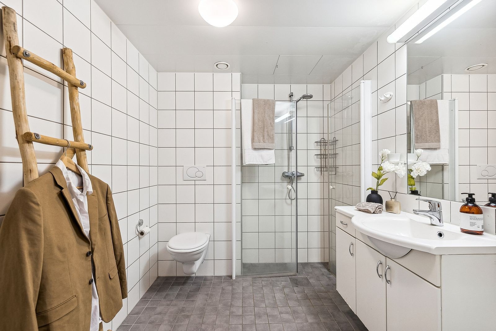 Flislagt baderom med nedfelt servant, klosett, dusjhjørne og opplegg til vaskemaskin Galleribilde