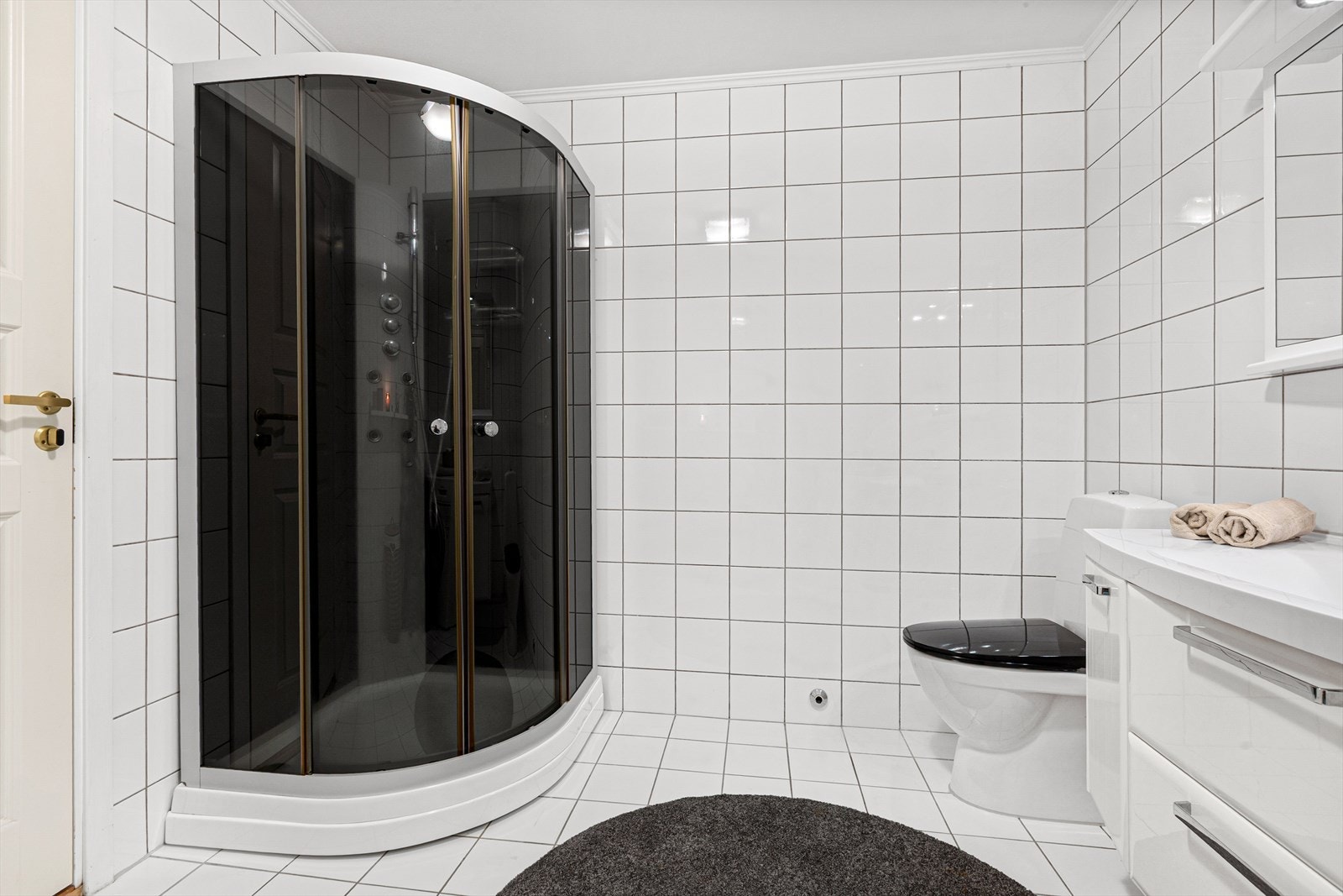 Badet er utstyrt med heldekkende servant med underskap, speil med lys, toalett og dusjkabinett Galleribilde