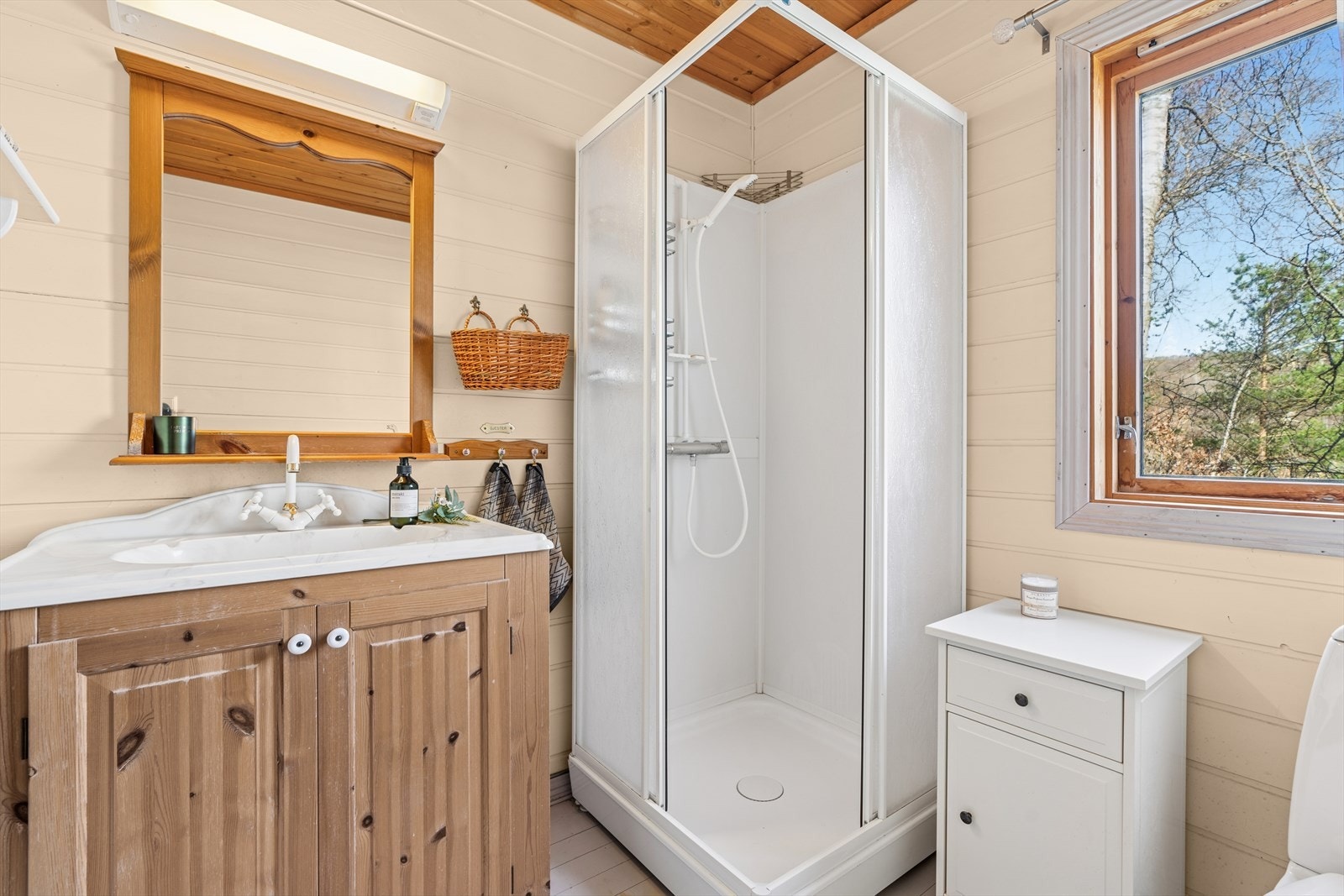 Badet er fra byggeår og er innredet med toalett, baderomsmøbel med servant og dusjkabinett. Galleribilde