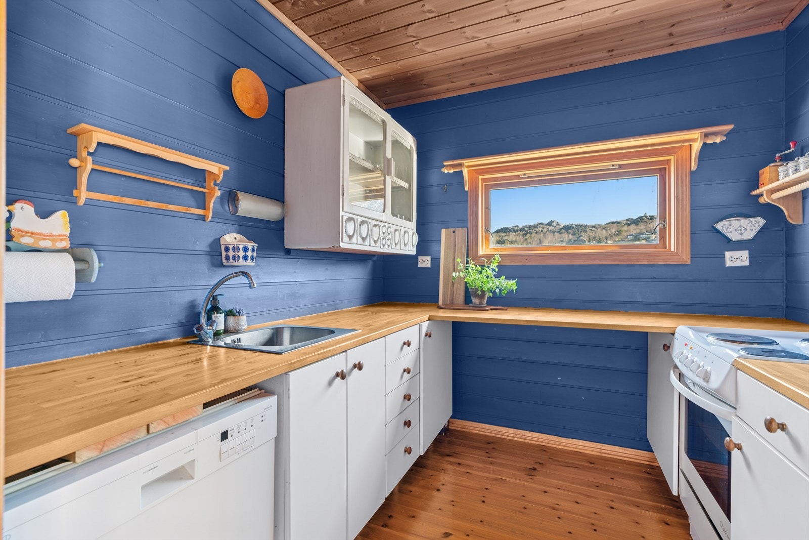 Kjøkkenet har innredning fra byggeår med hvite glatte fronter og benkeplate i tre. Galleribilde