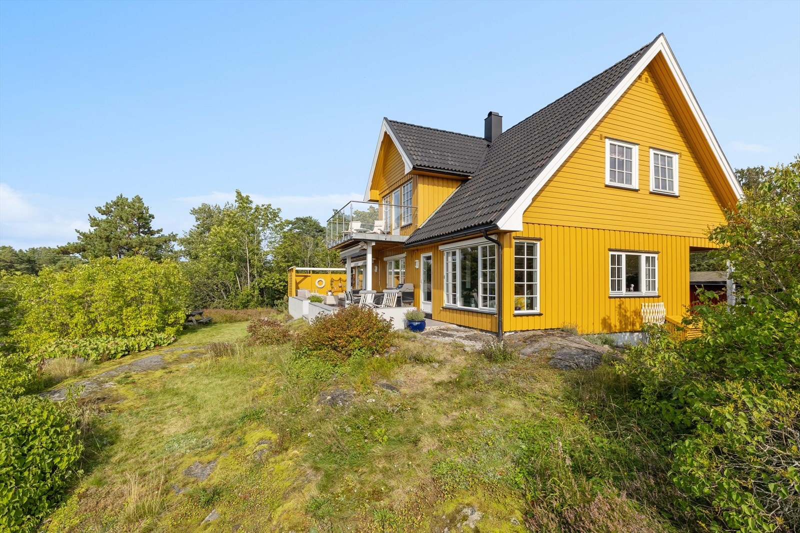 Tomten er pent opparbeidet med plen, beplantning, vei og parkeringsareal. Galleribilde