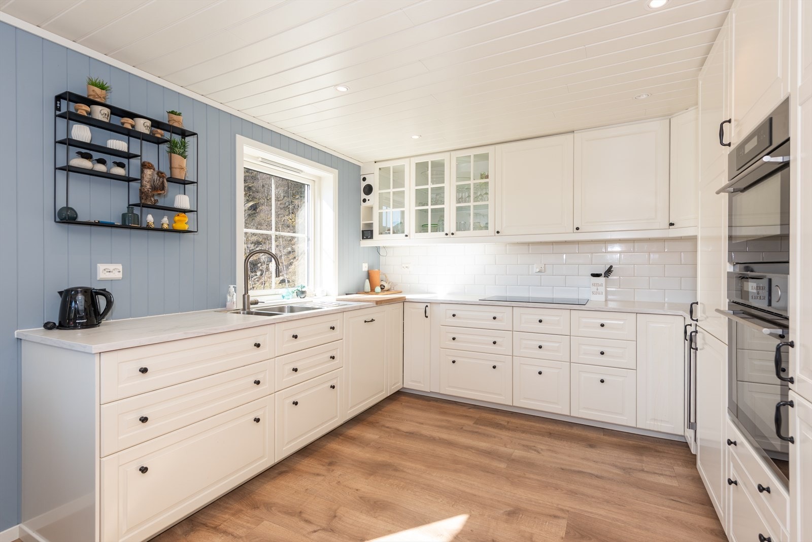 Det er Ikea kjøkken med hvite profilerte fronter, laminat benkeplate og dobbel vaskekum. Galleribilde