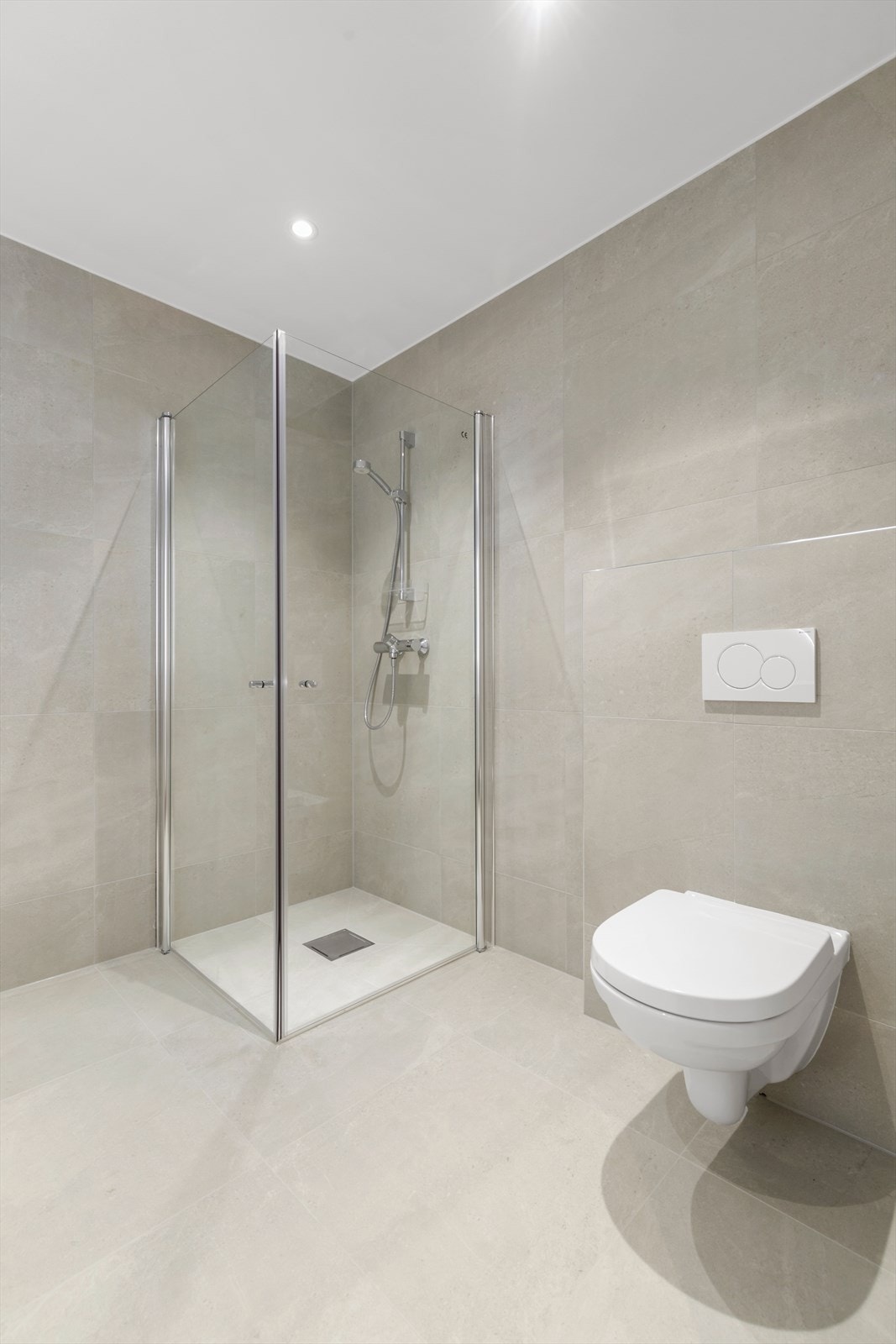 Helfliset bad med 60*60 flis, vegghengt toalett, stor dusjnisje og praktisk baderomsinnredning. Galleribilde