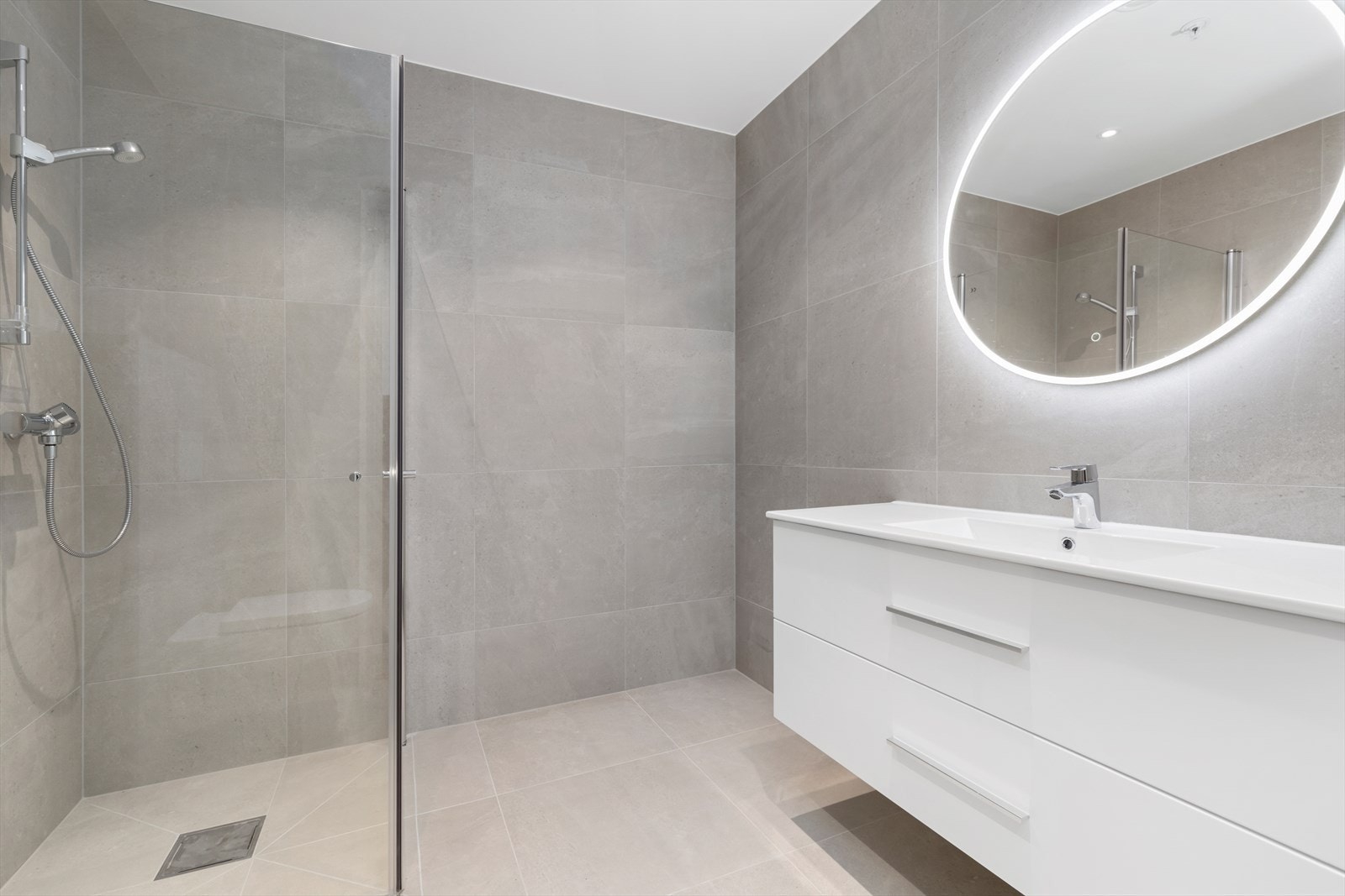 Helfliset bad med 60*60 flis, vegghengt toalett, stor dusjnisje og praktisk baderomsinnredning. Galleribilde